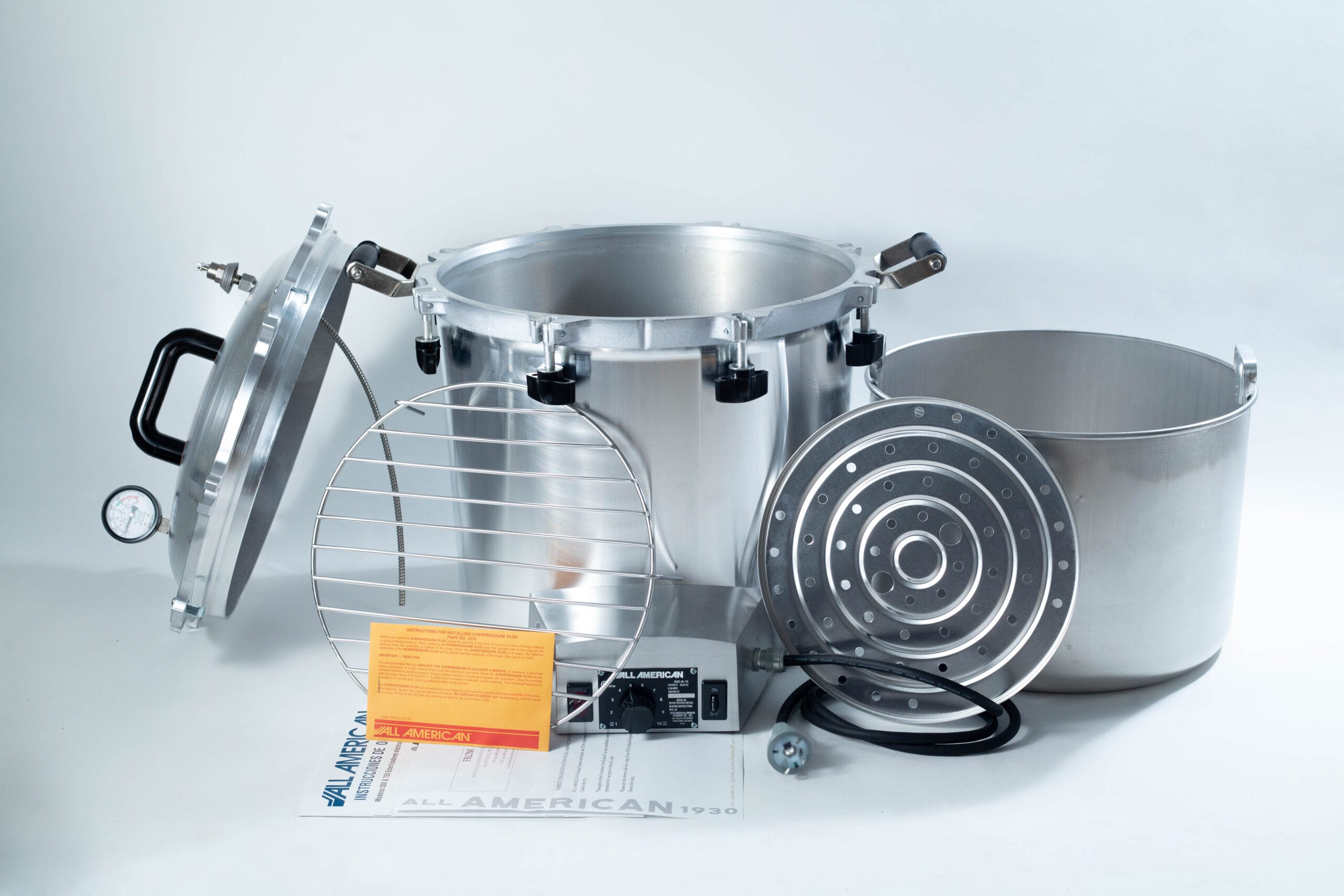 Large silver autoclave with lid, metal rack, inner pot, instructions, and power lead displayed on a white background.