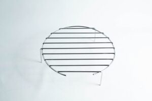 A round metal cooling rack with three legs on a plain white background.