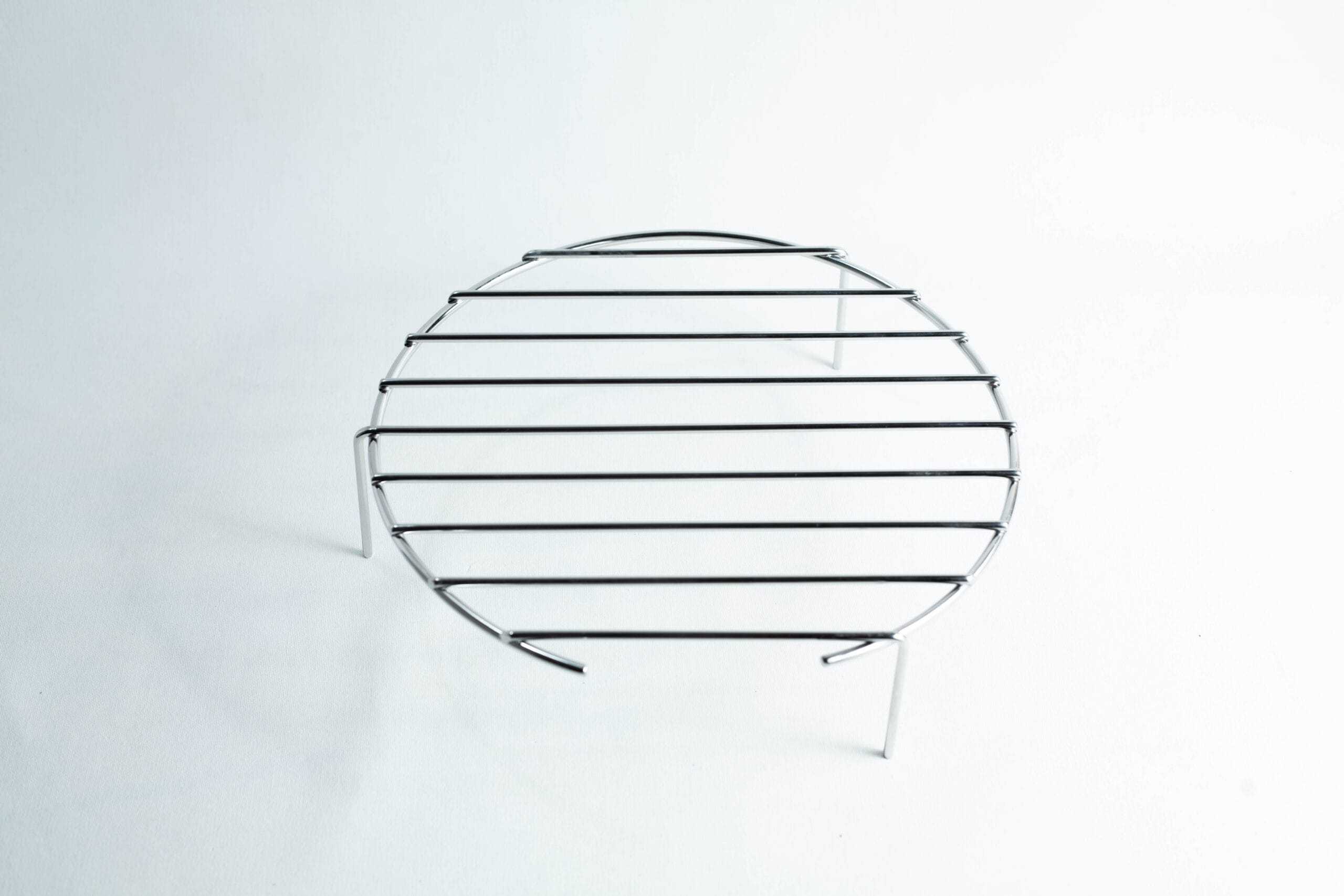 A round metal cooling rack with three legs on a plain white background.