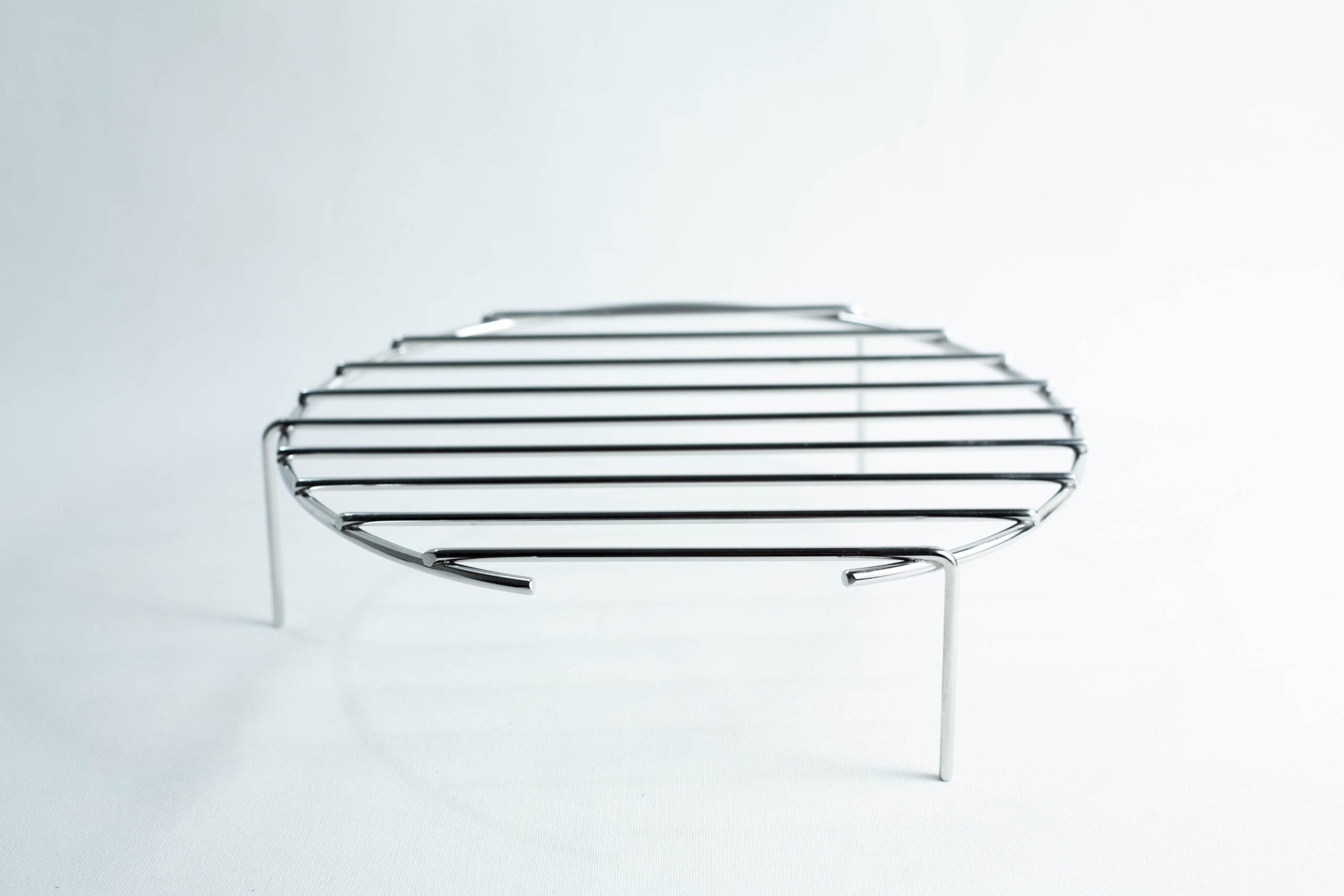 A small round metal grill rack on three legs, set against a plain white background.