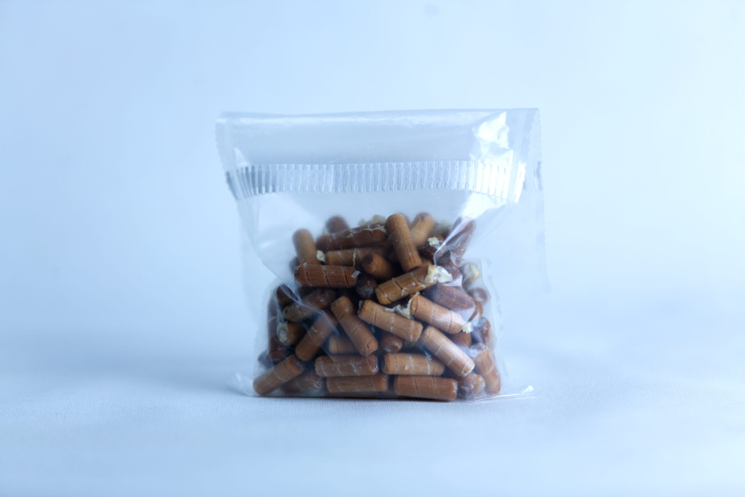 A clear plastic bag of Log Dowel Mushroom Plug Spawn (Ganoderma steyaertanum), Native Australian Reishi, is shown against a light blue background.