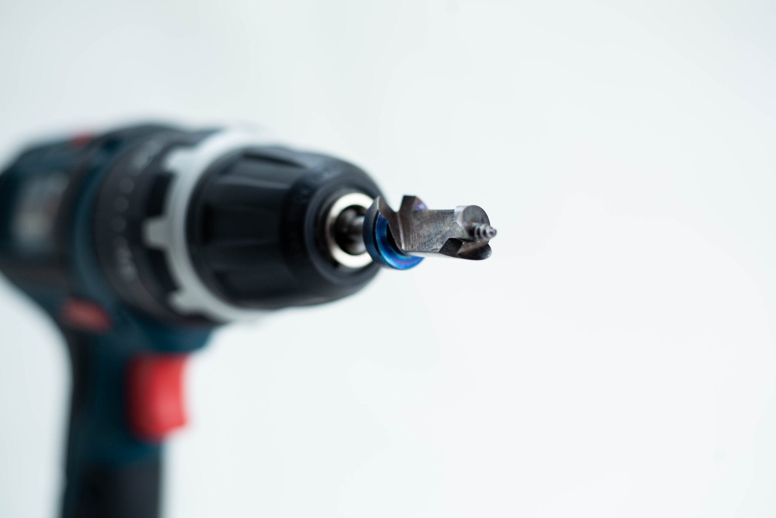 Close-up of a power drill with a specialised drill bit, set against a plain white background.