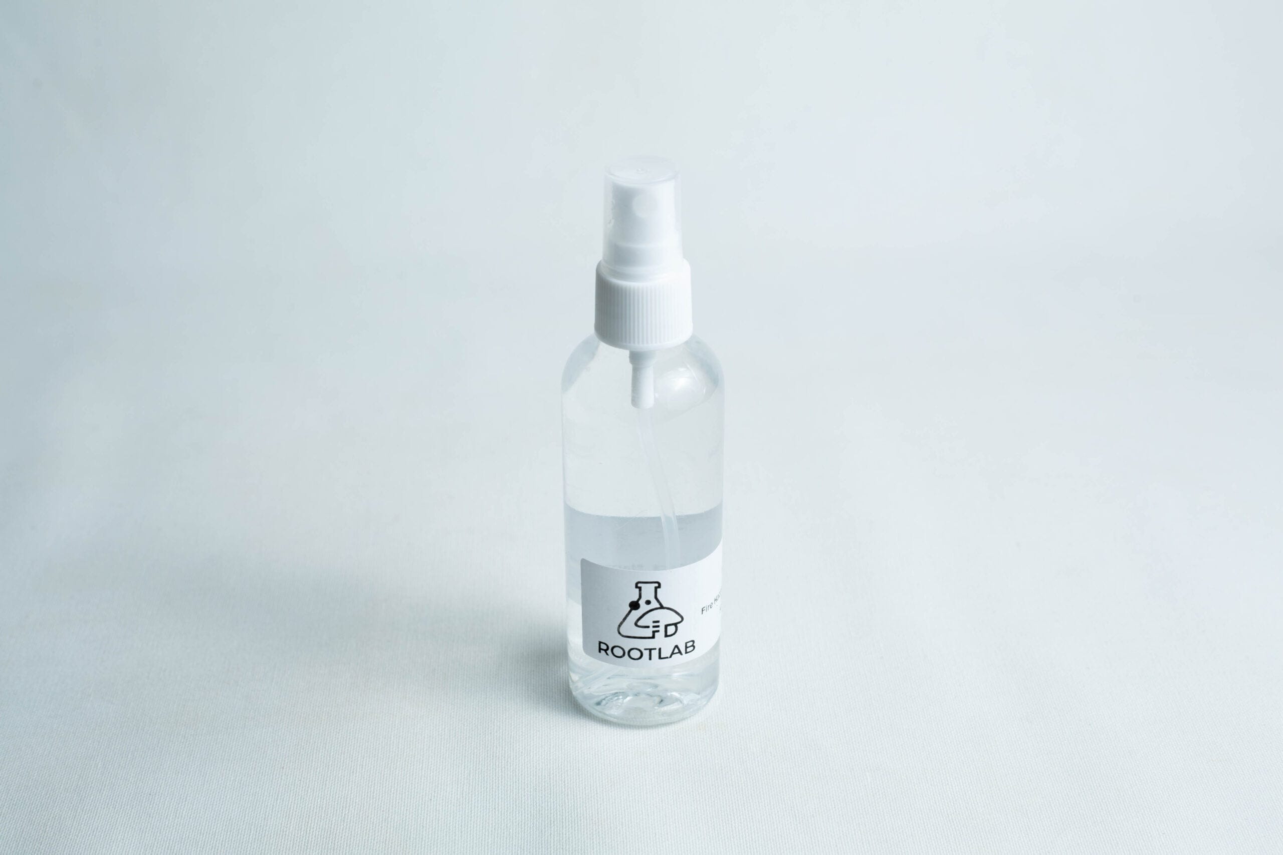 A clear 100ml spray bottle labelled ROOTLAB with a laboratory flask logo, containing 70% isopropyl alcohol, is placed on a white background.