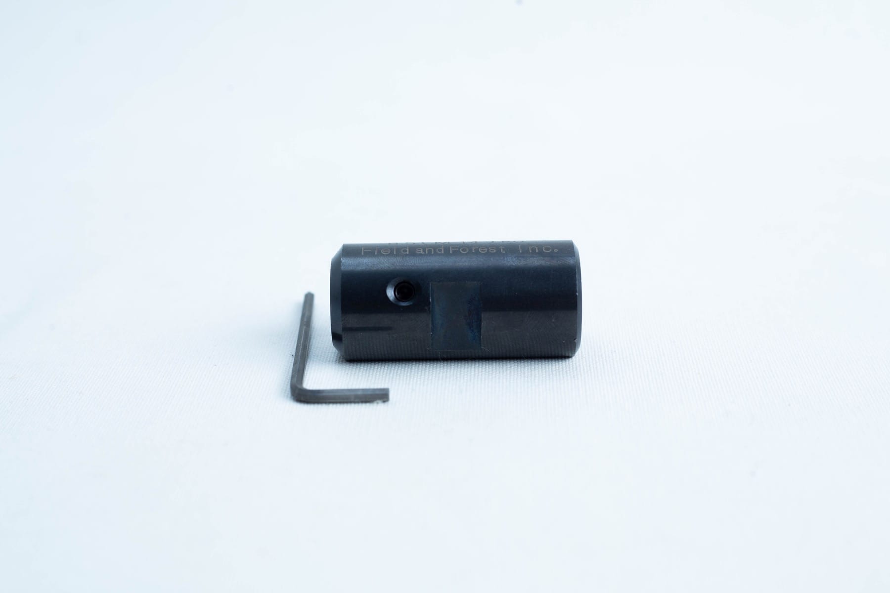 A small black cylindrical tool and an L-shaped hex key on a white background.