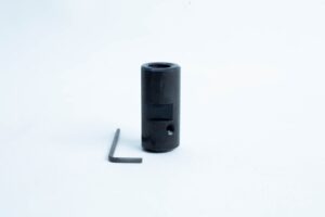 A black metal cylinder with a hole, next to a small L-shaped hex key on a white background.