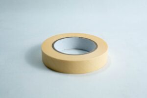 A roll of beige masking tape on a white surface.