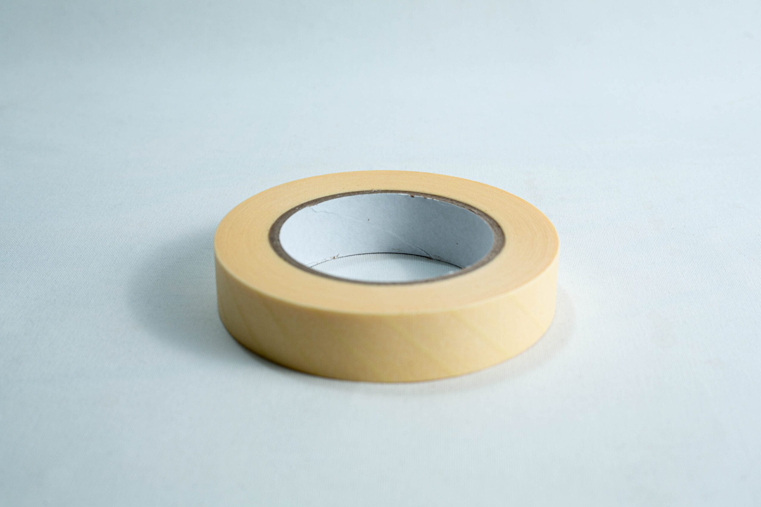 A roll of beige masking tape on a white surface.