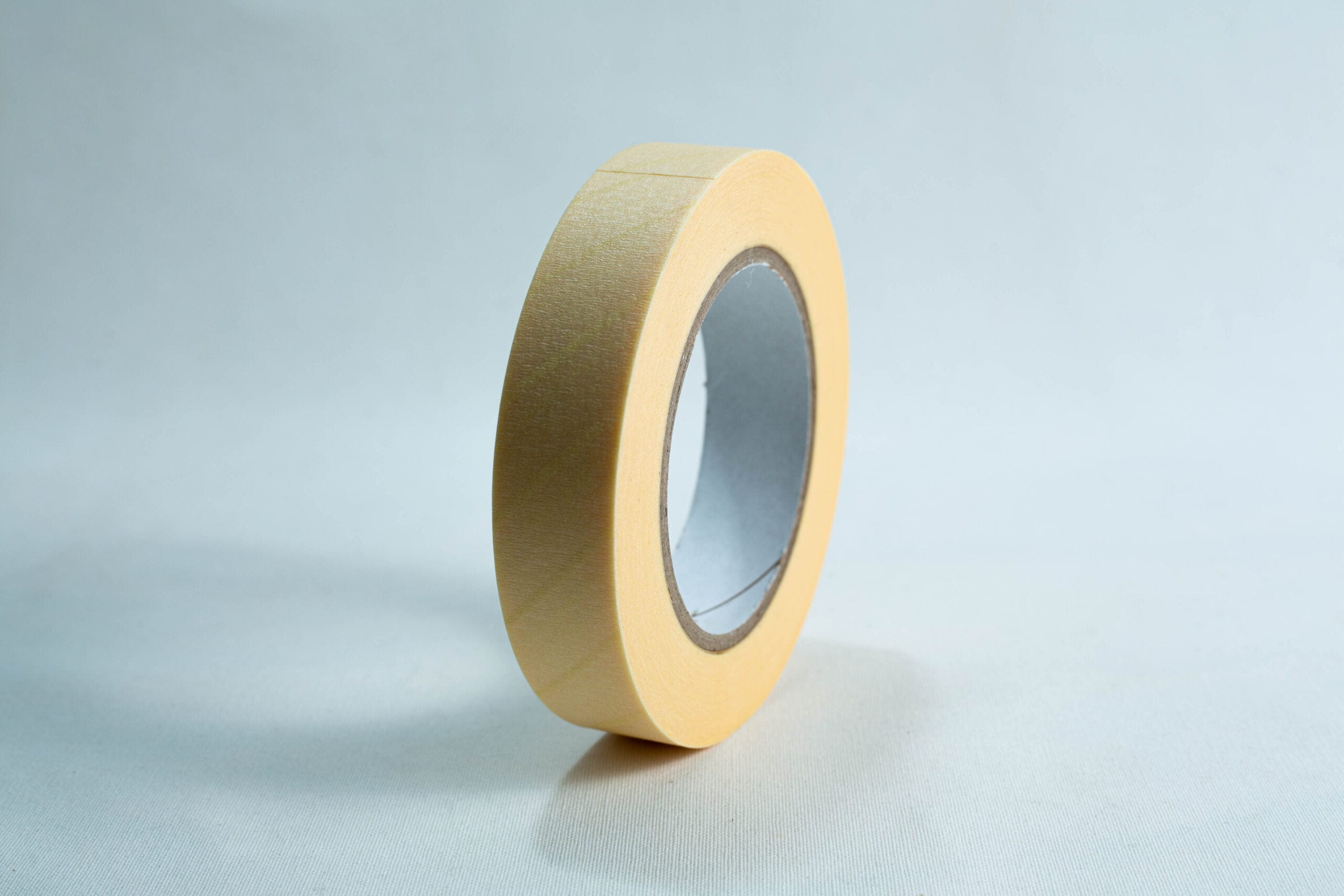 A single roll of beige masking tape standing upright on a plain white background.