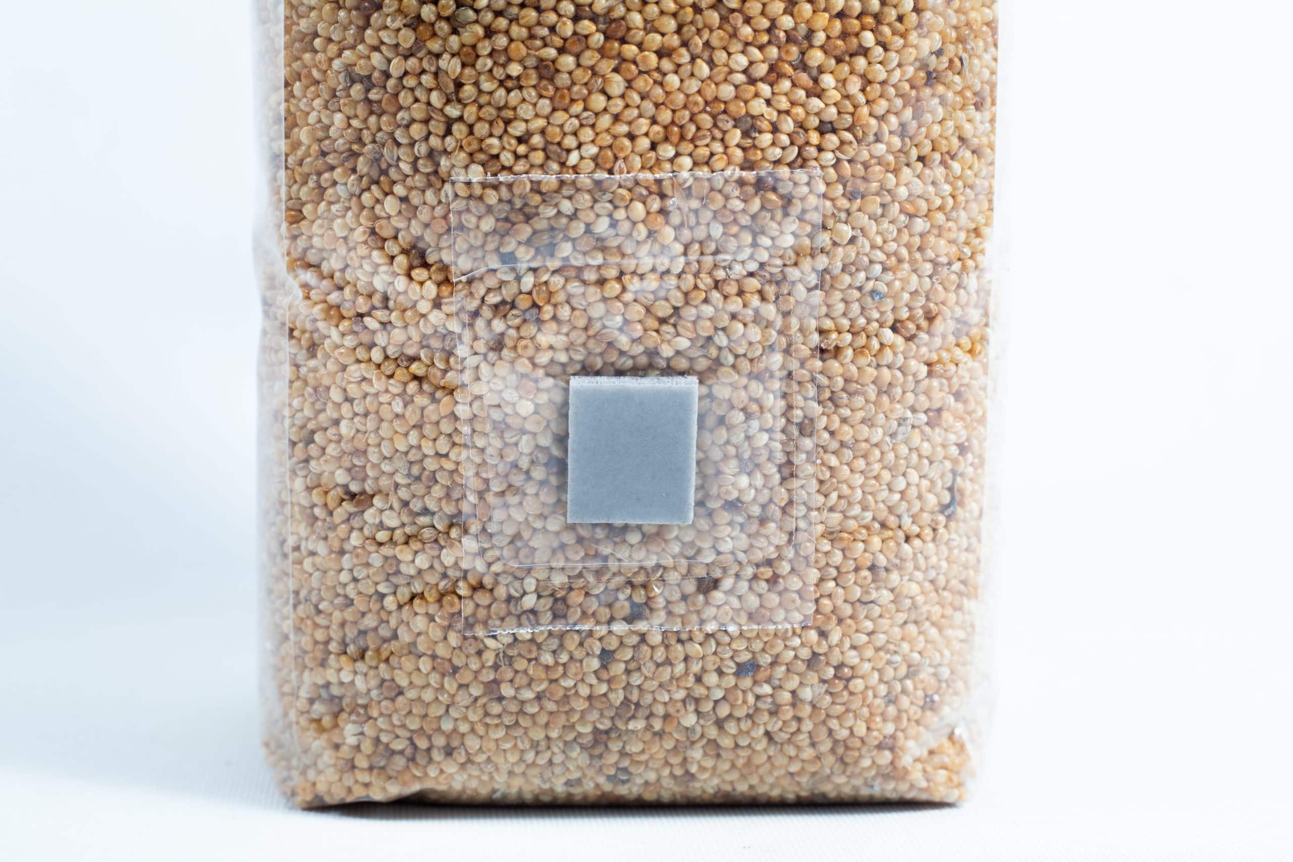 A clear plastic bag of millet pre-sterilised mushroom grains with injection port and digital instructions, sealed with a grey square label.