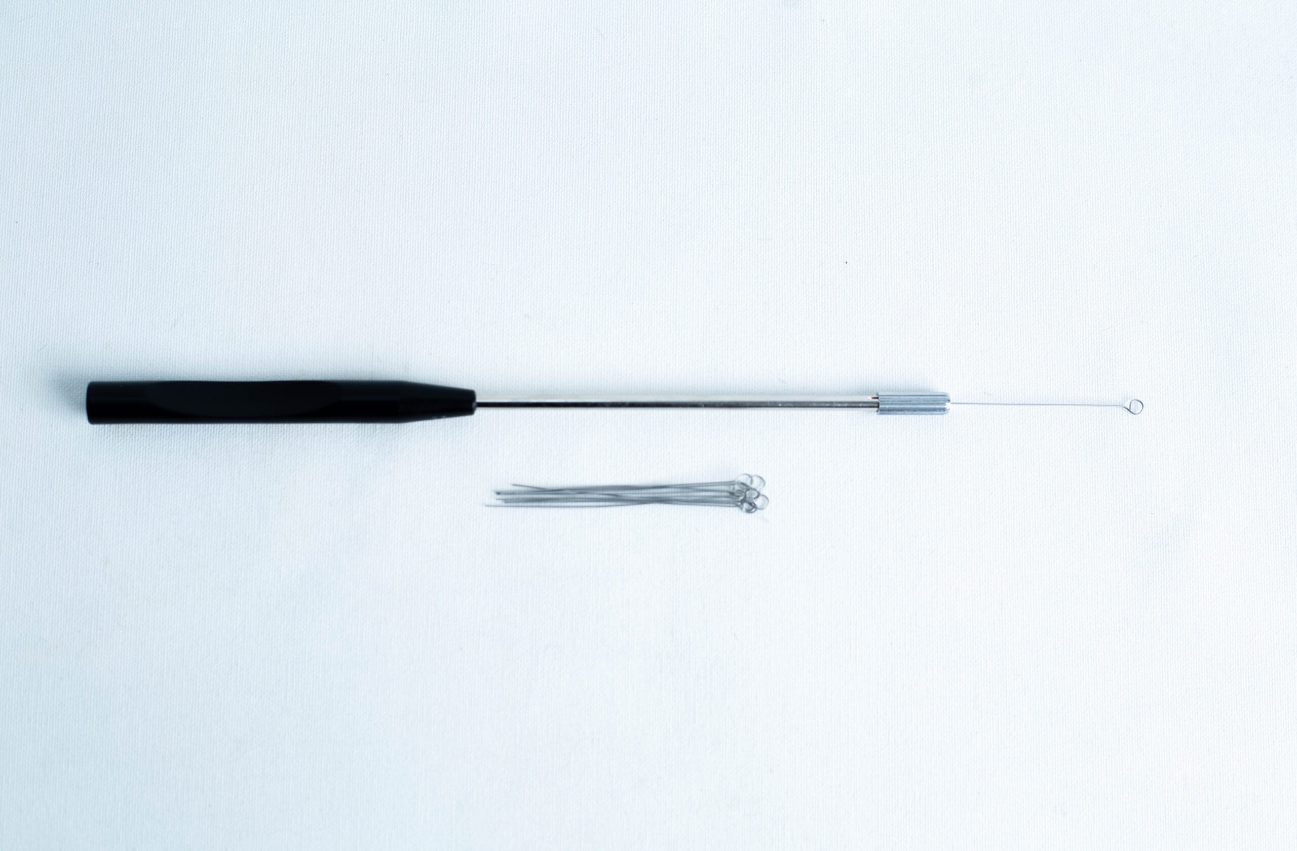 A black-handled inoculation loop and several metal loops on a white background.
