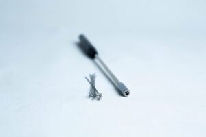 A precision screwdriver and several small screws on a white surface.
