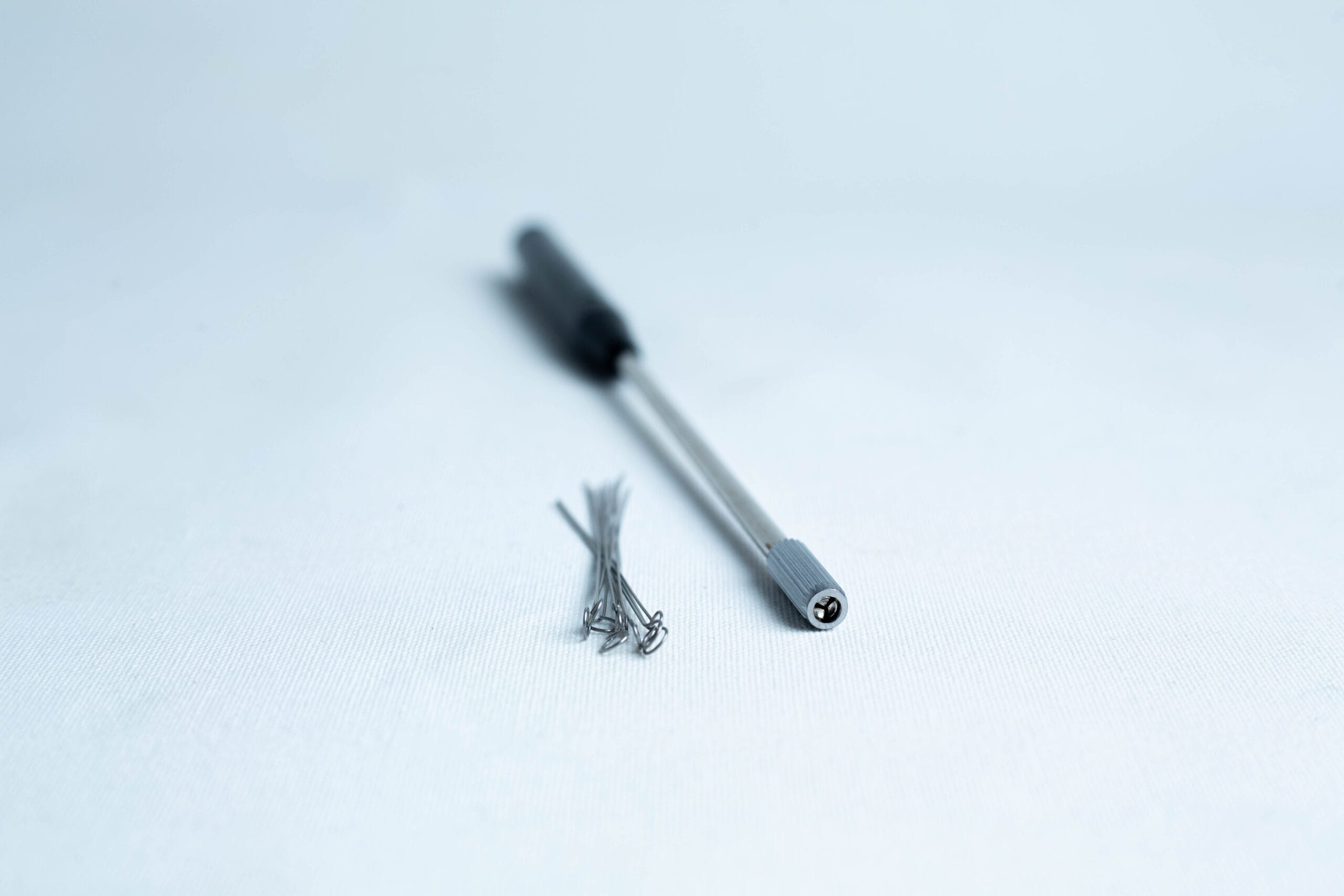 A precision screwdriver and several small screws on a white surface.