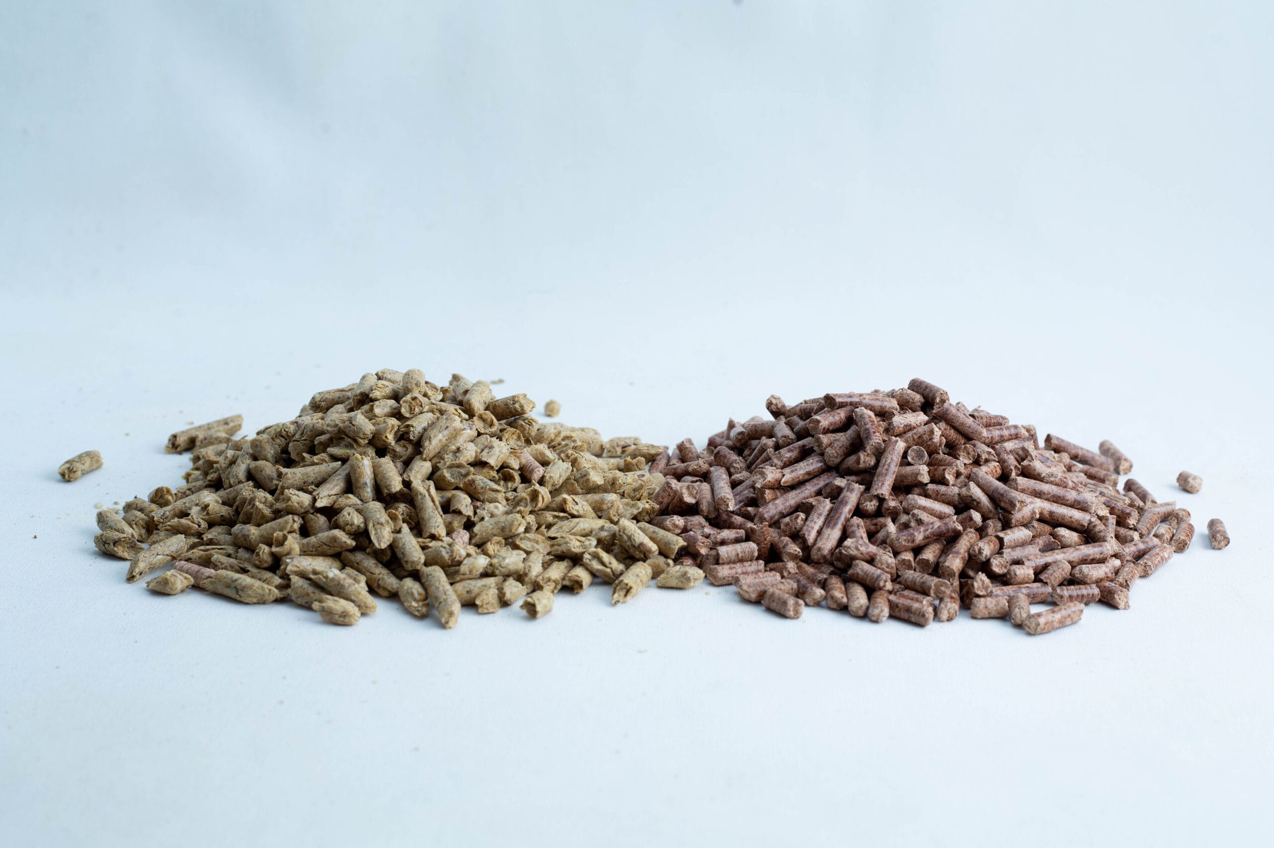 Two piles of brown and beige animal feed pellets on a white background.