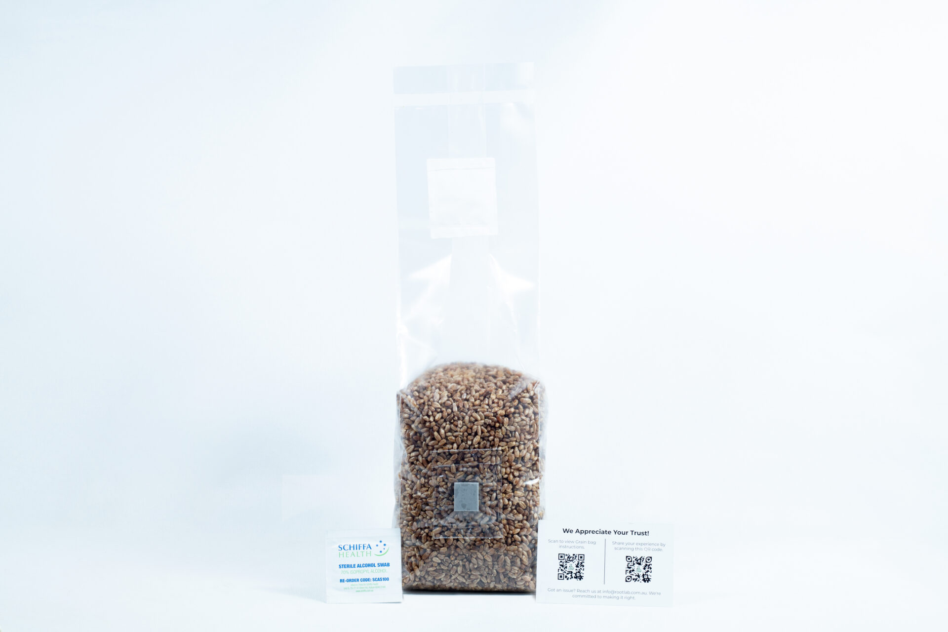 A clear bag of organic pre-sterilised rye grain for mushroom cultivation with injection port and air filter, plus two business cards in front—all on a white background.