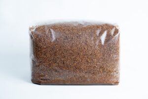 A clear plastic bag contains finely ground brown Masters Mix Mushroom Substrate, made from sawdust and soya pellets.