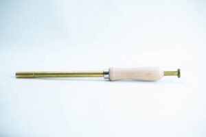A brass and wood tool with a cylindrical handle and narrow metal shaft on a white background.