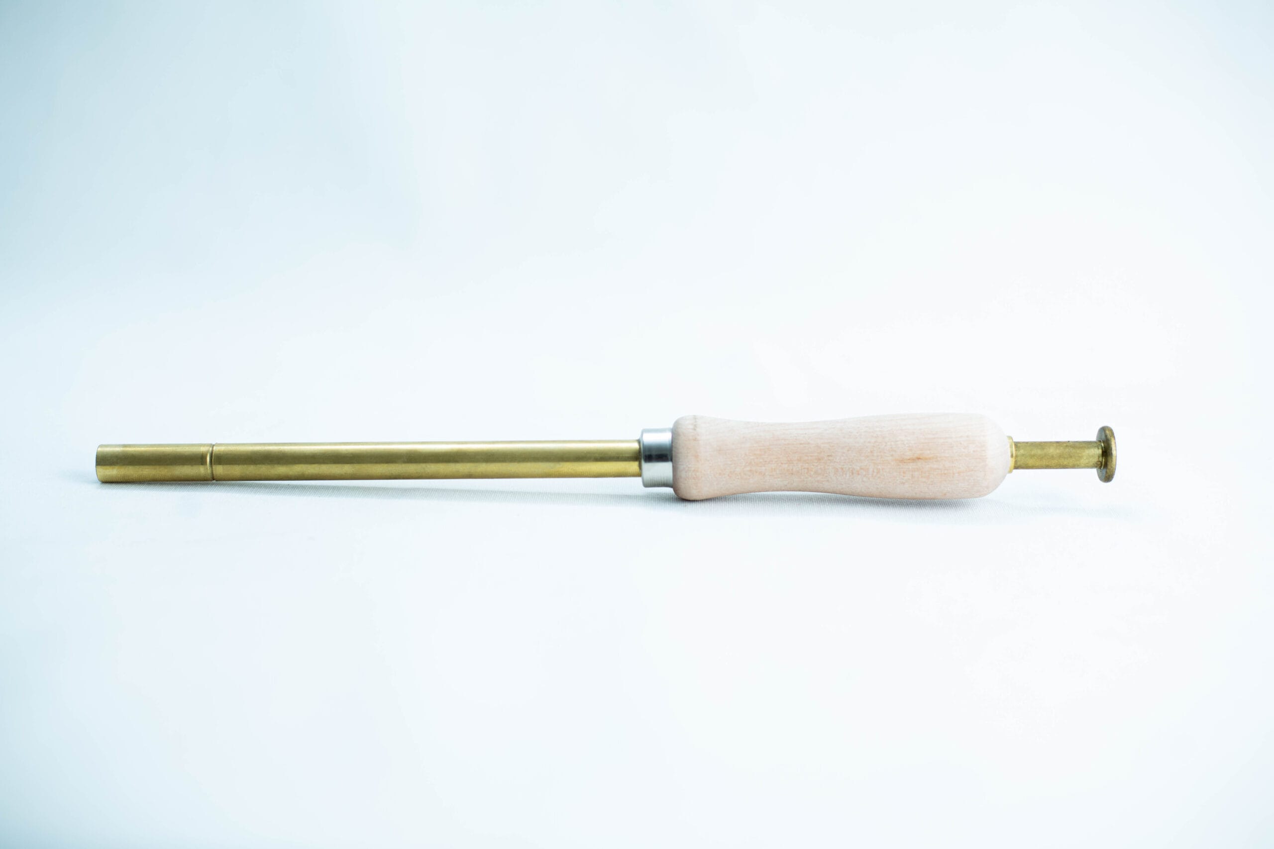 A brass and wood tool with a cylindrical handle and narrow metal shaft on a white background.