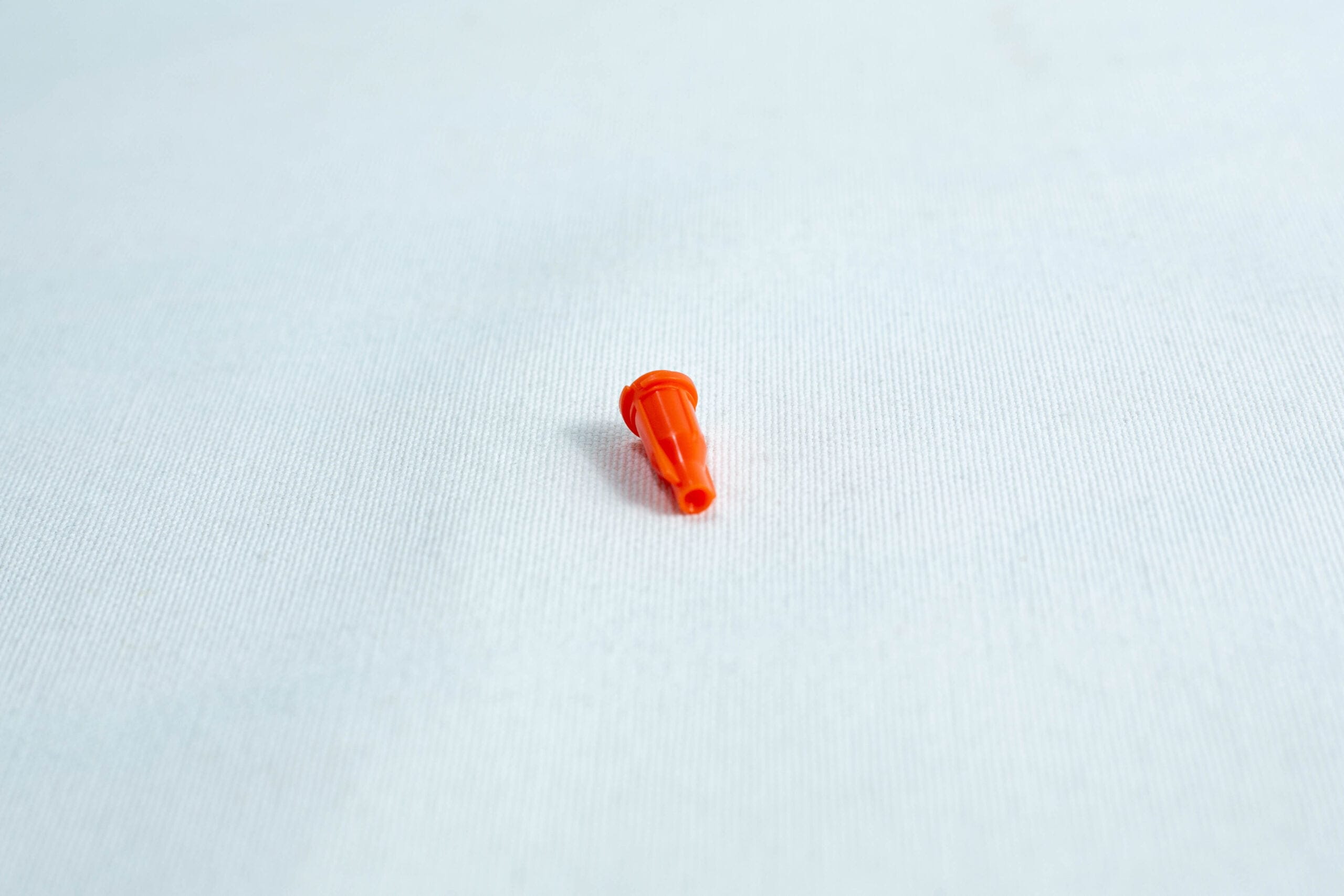 Small orange plastic object on a plain white surface.