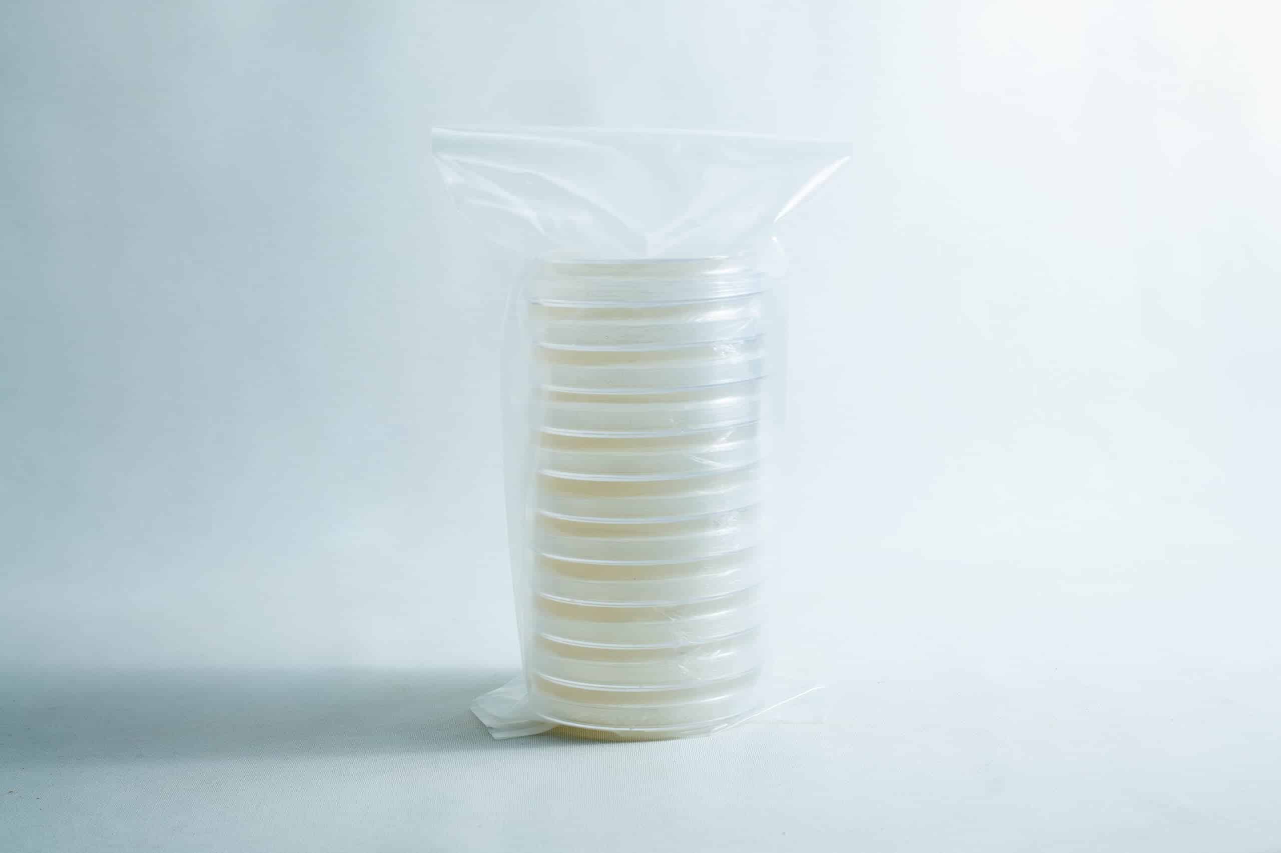 A stack of clear petri dishes wrapped in a plastic bag on a plain white background.