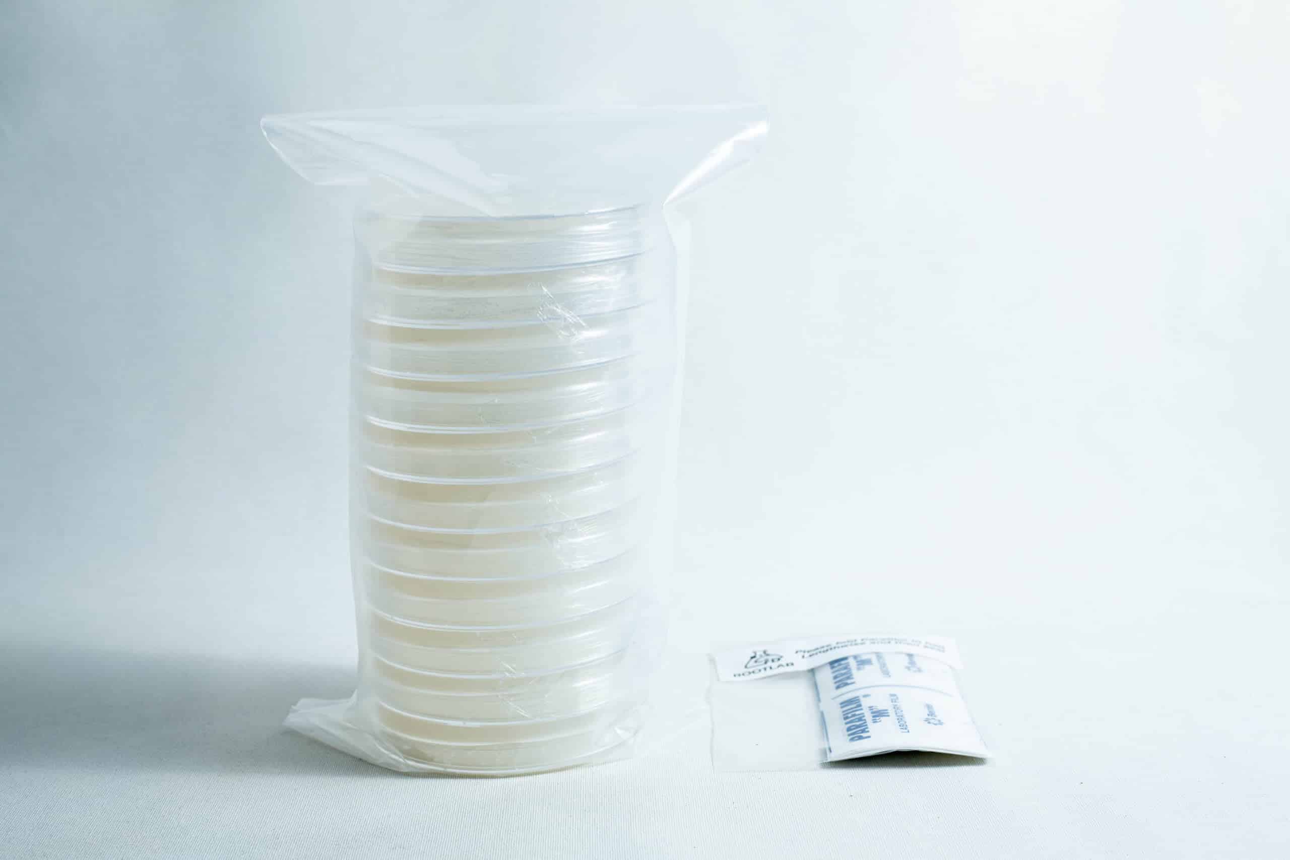 A stack of sealed petri dishes and a small packet on a white surface with a plain background.