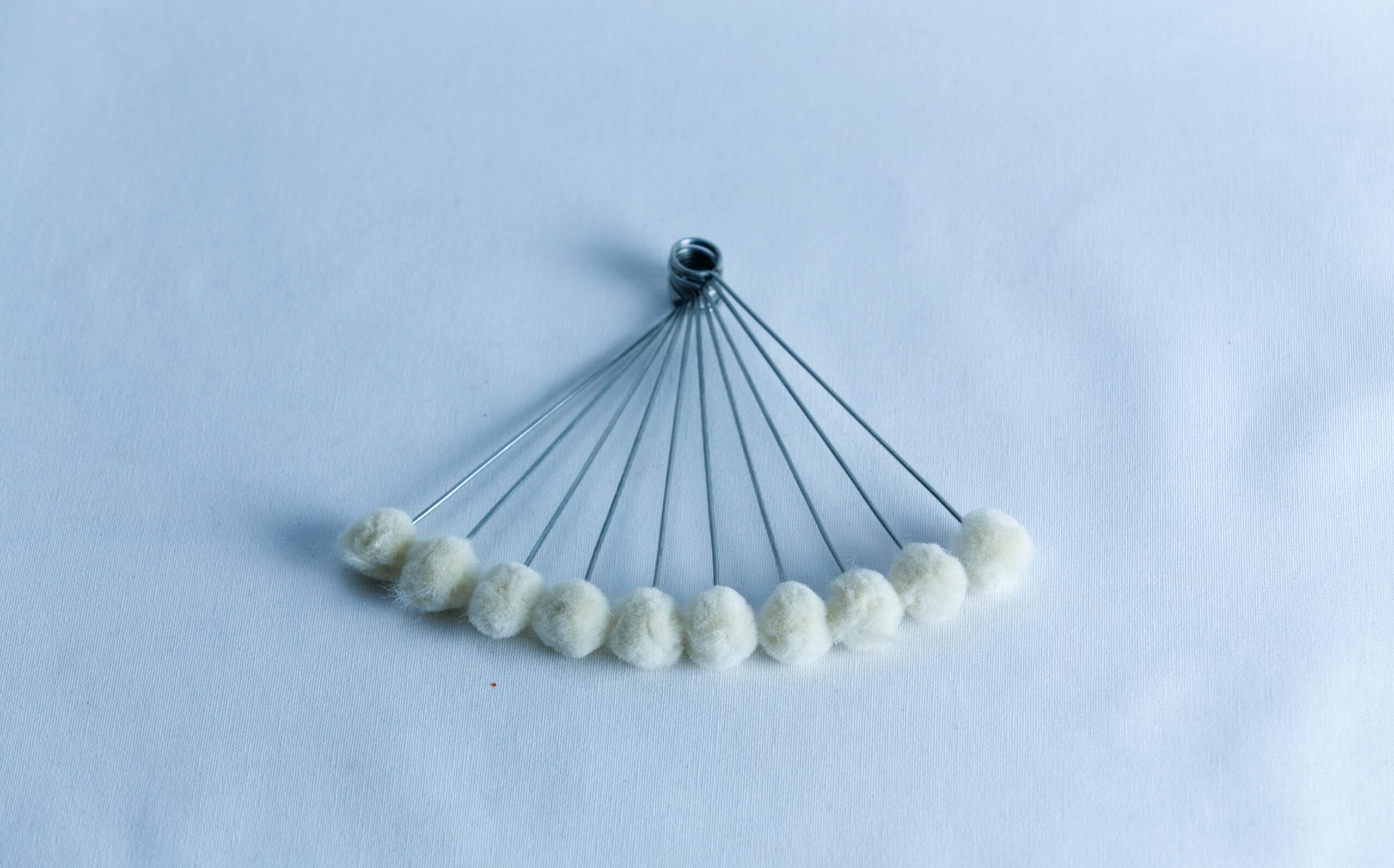 Ten metal rods with white cotton tips, arranged in a fan shape on a white background.