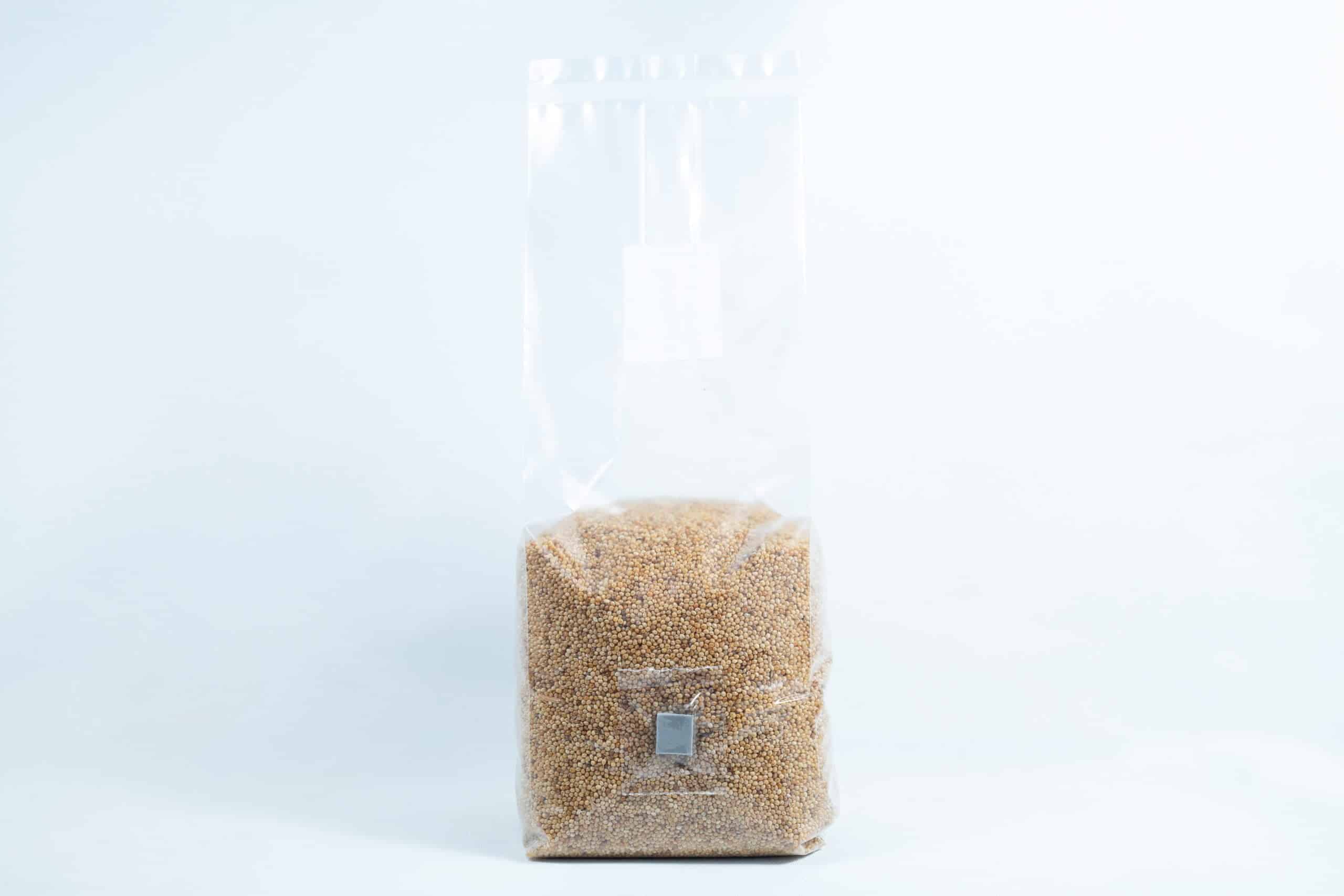 A clear plastic bag of Millet Pre-Sterilised Mushroom Grains with injection port and digital instructions, sealed at the top, shown on a white background.