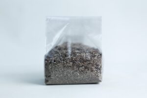 A clear plastic bag filled with sand and small pebbles, set against a plain white background.
