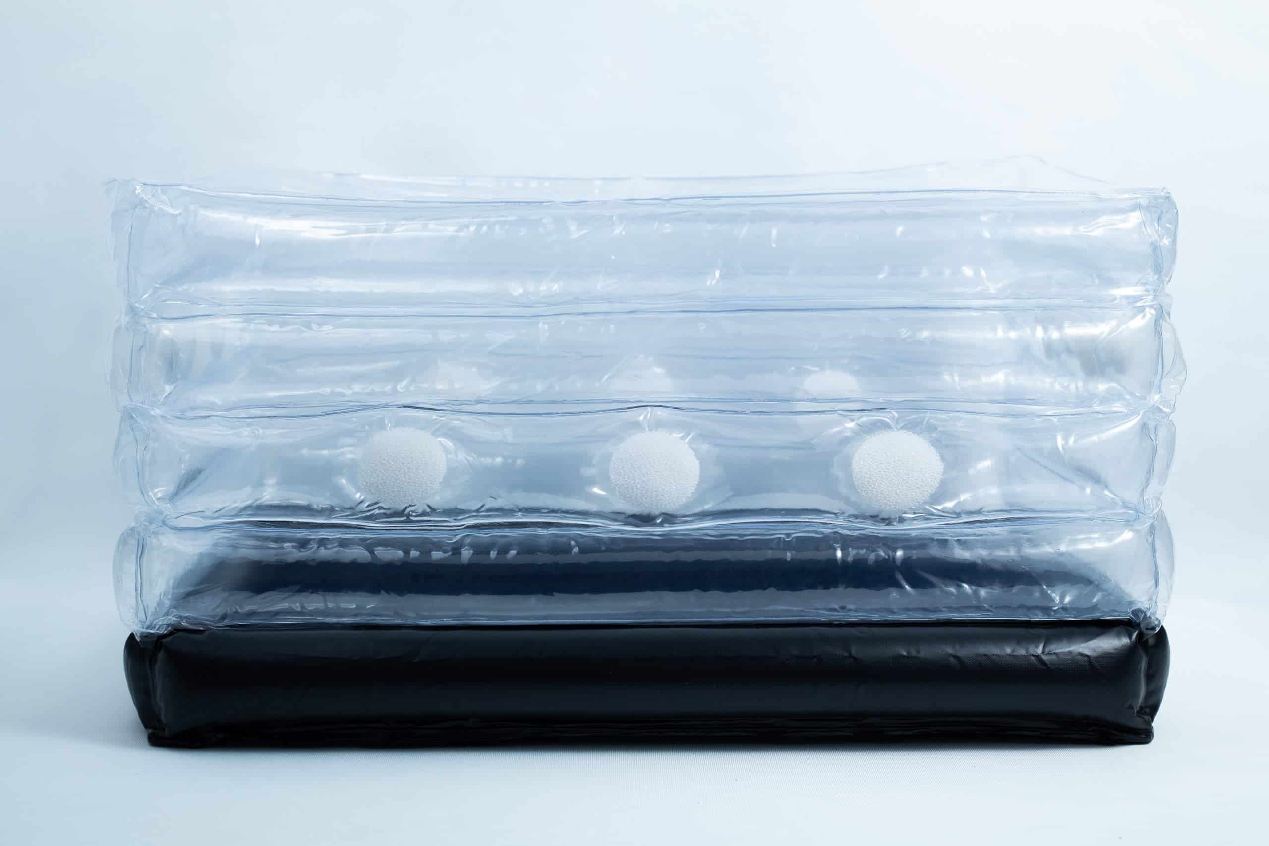 Clear inflatable plastic packaging with white foam balls inside and a black base, set against a plain background.