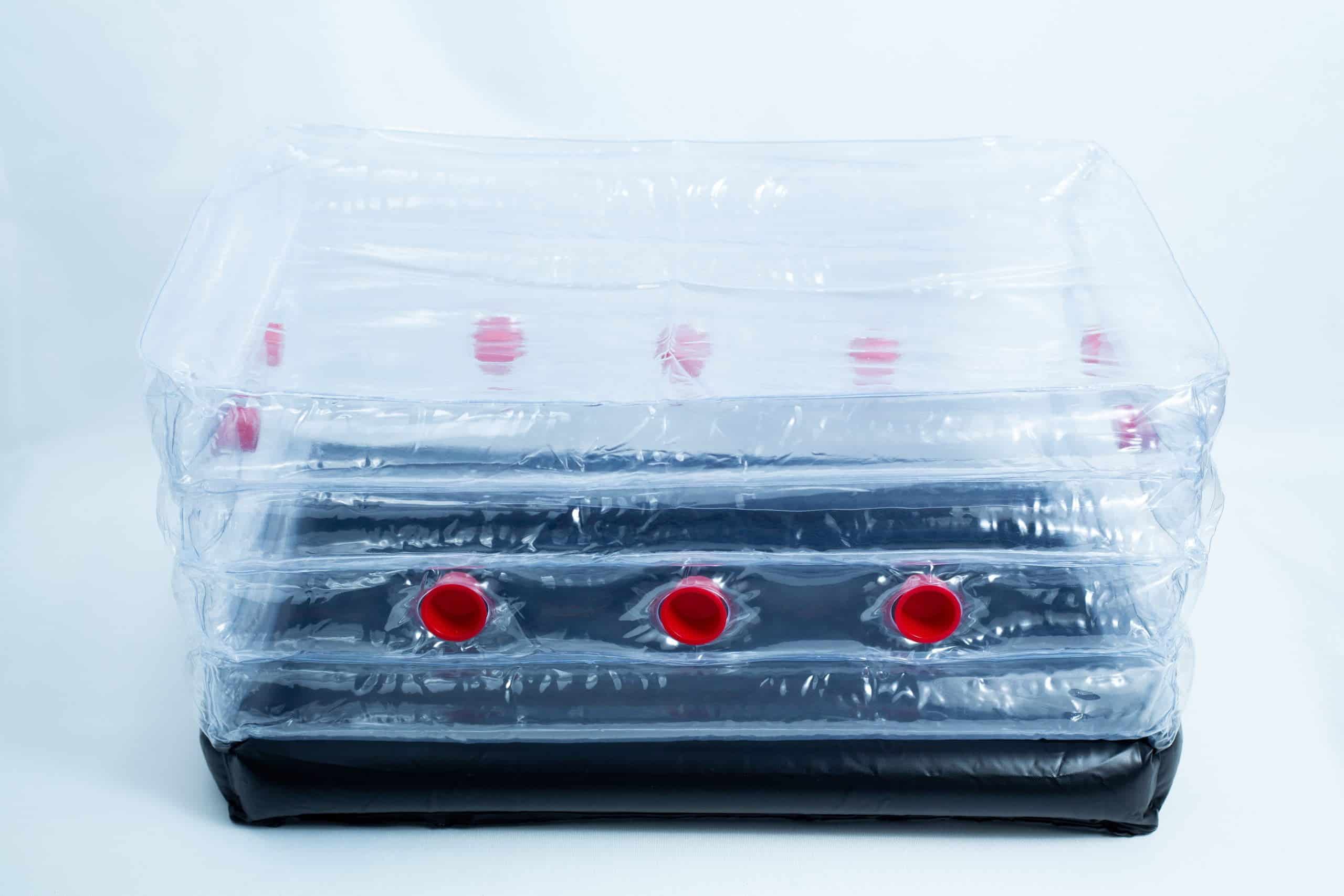 A clear inflatable plastic box with red caps and a black base, set against a white background.