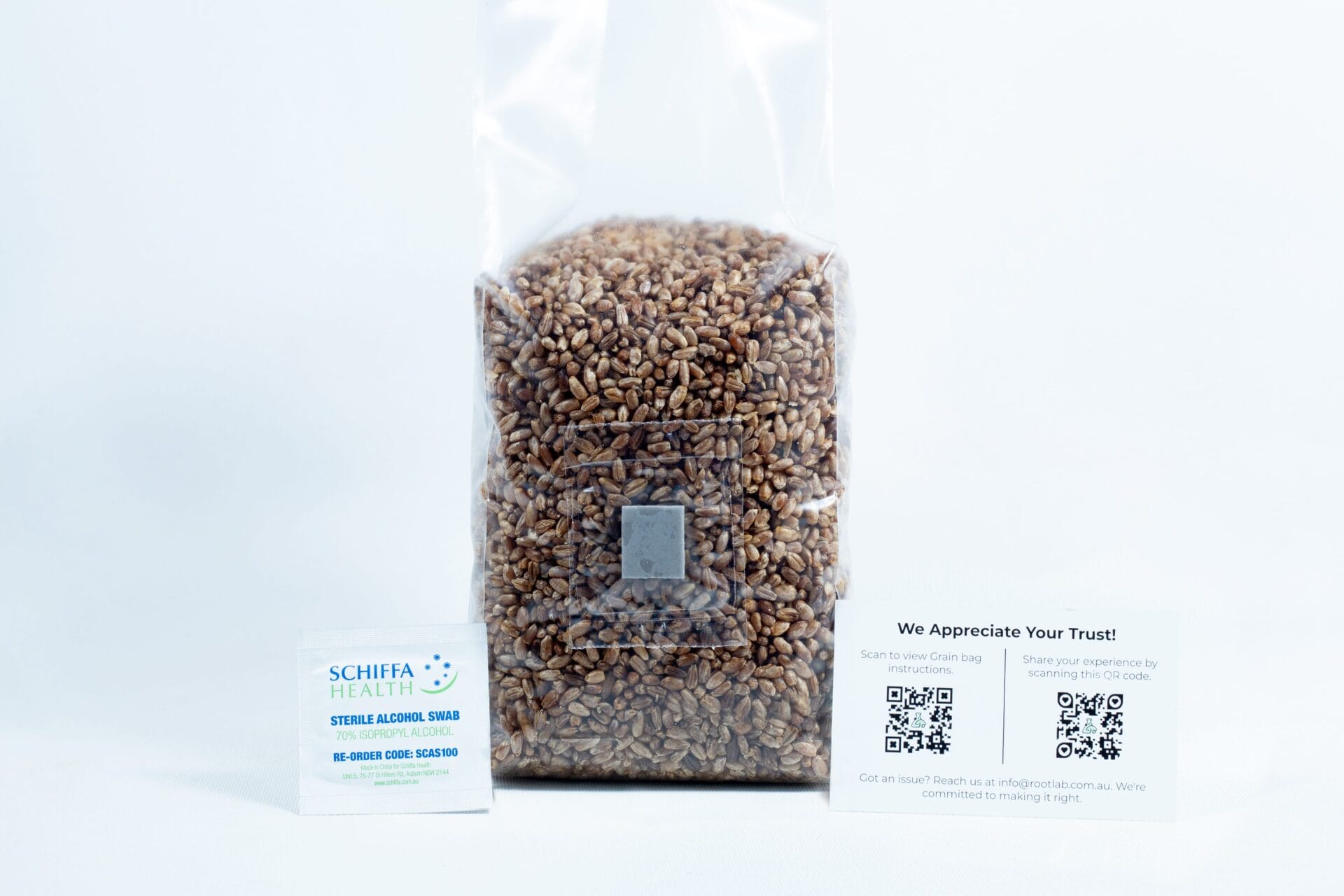 A sealed bag of grains for the Monotub Mushroom Growing Kit–Premium, accompanied by a packet and a card displaying QR codes, is placed beside it on a white background.