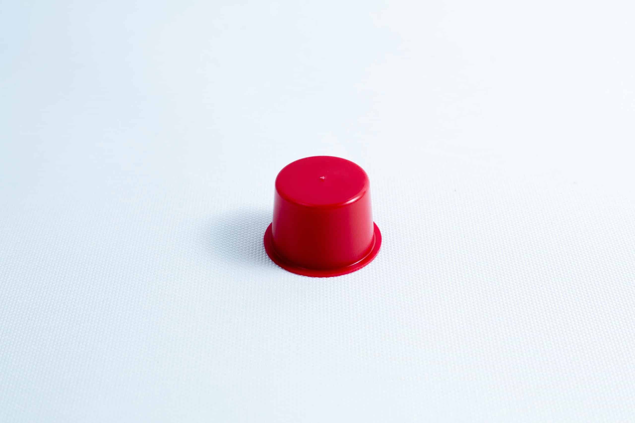 A small red plastic cup turned upside down on a plain white surface.