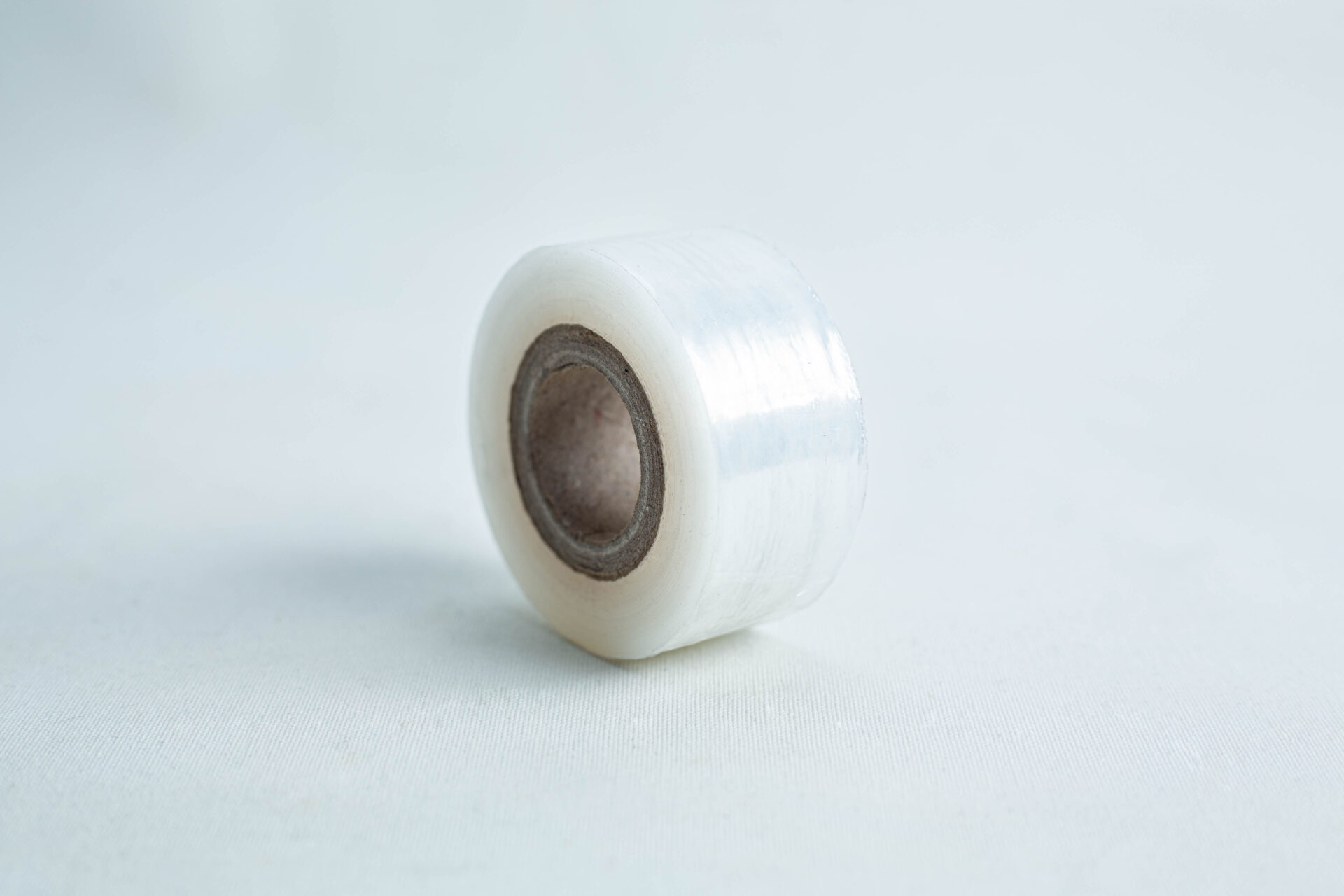 A small roll of Grafting Tape to seal agar plates or for plant grafting, with a brown cardboard core, rests on a light surface.