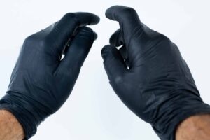 Two hands wearing black disposable gloves are held up against a plain white background, suggesting readiness for hygienic tasks often paired with a Disposable Face Mask/Unit Individually wrapped.