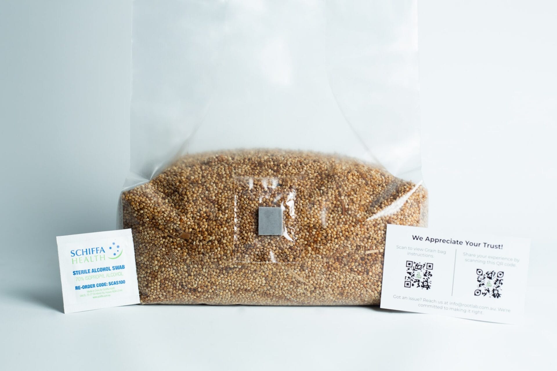 Clear bag of seeds with two business cards placed on either side against a white background.