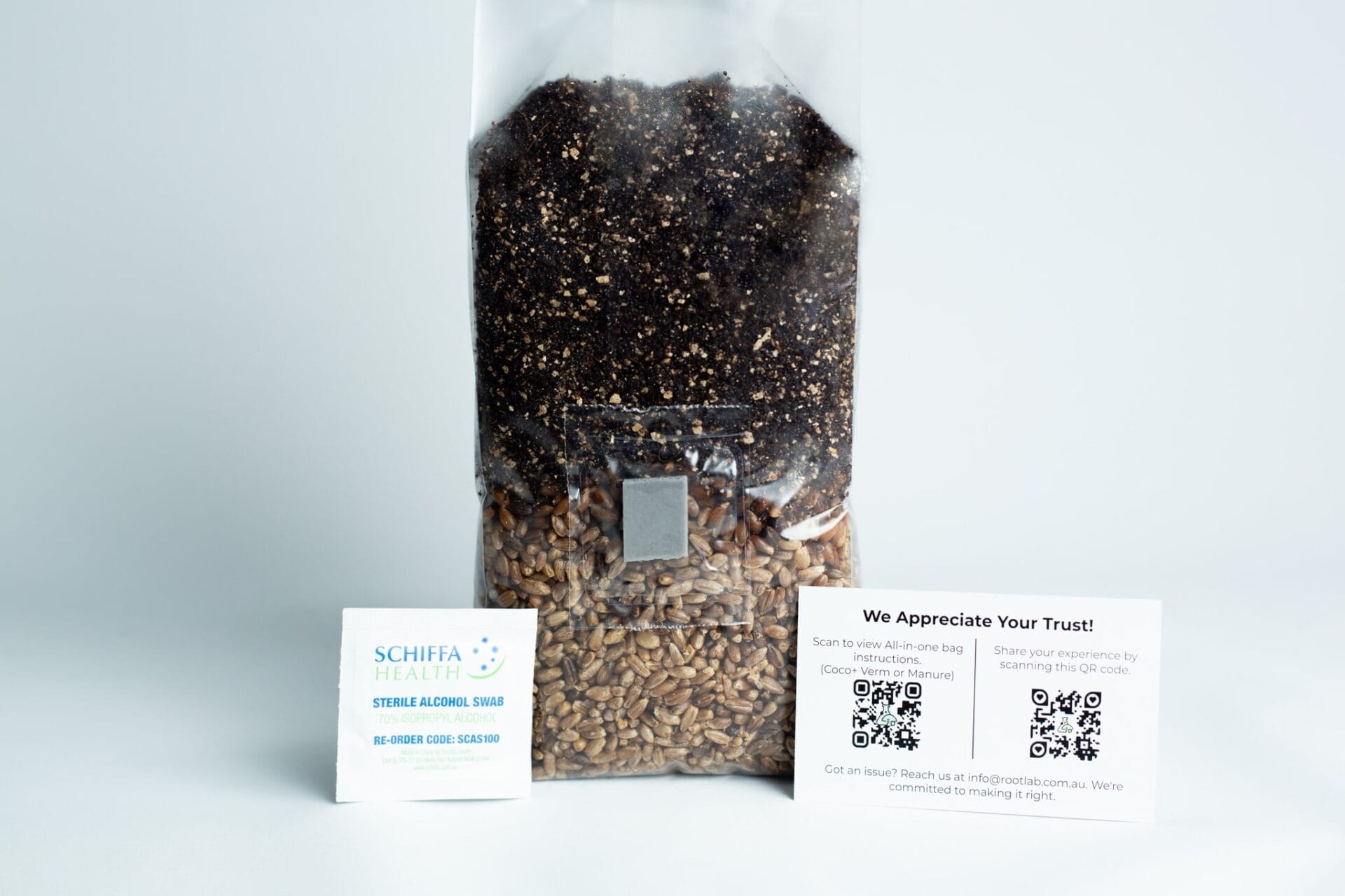 A sealed bag of seeds and soil with two informational cards displayed in front of it on a white surface.