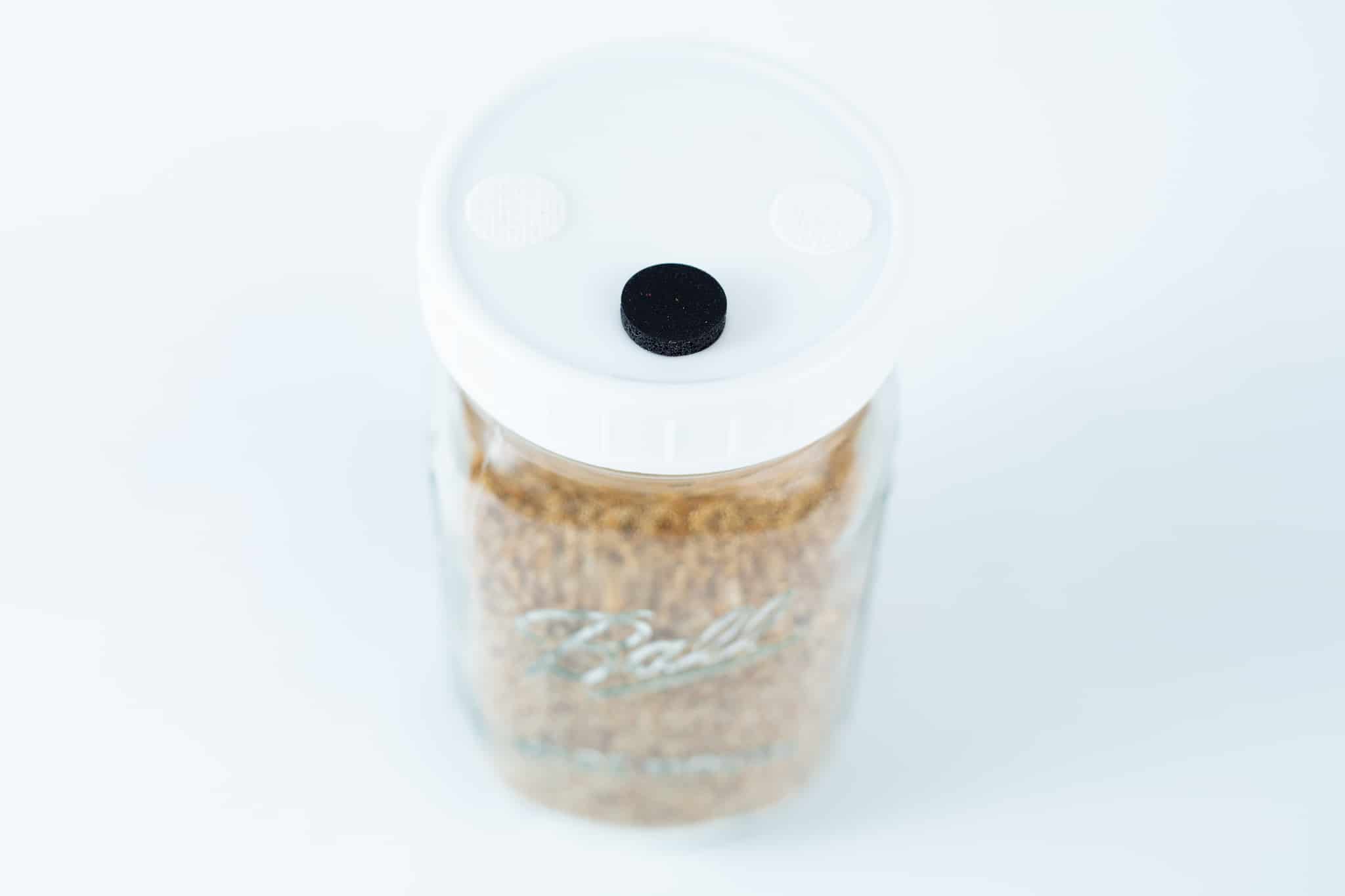 The Grain Jars Ball 1L Pre-Sterilised with a white lid and black centre dot comes filled with organic millet and rye grains in a reusable jar.