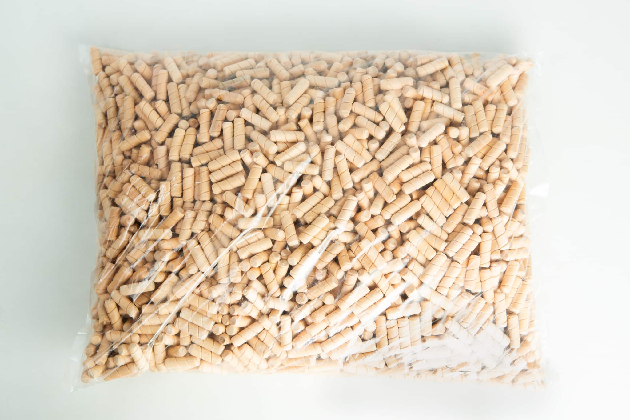 A clear plastic bag filled with small, cylindrical wooden pegs on a white surface.