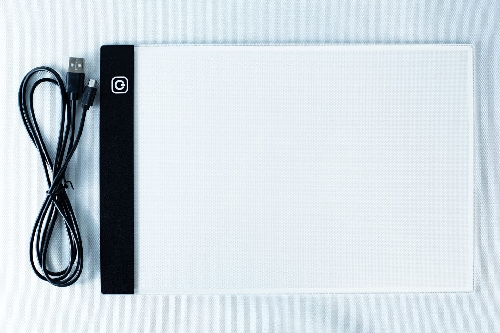 A USB cable and a flat, rectangular LED light pad for tracing on a white background.