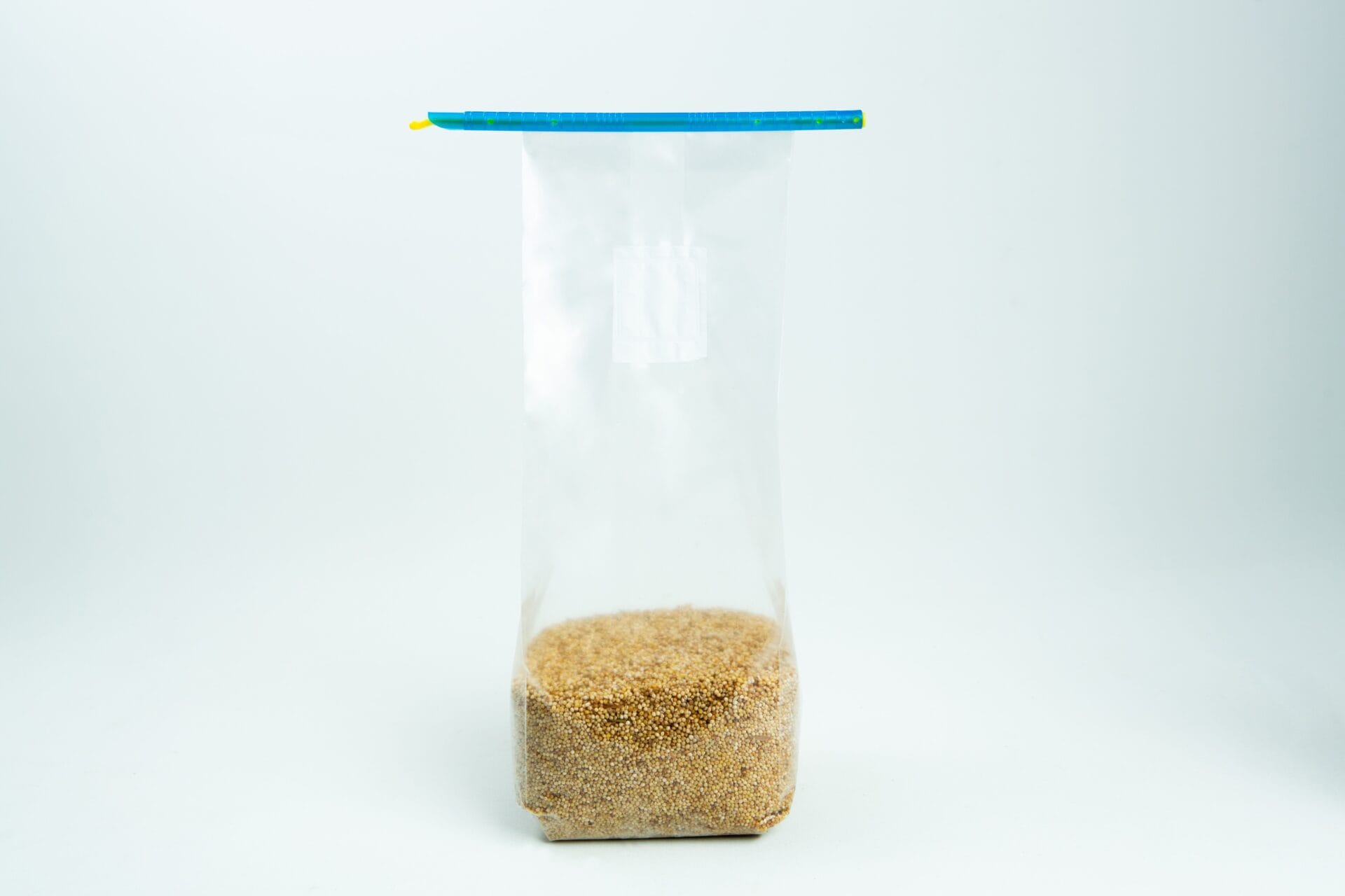 A clear plastic zip bag partially filled with brown granulated sugar, standing upright on a white background.