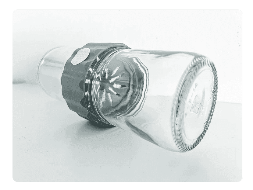 A Plant Cell Biocoupler™ Glass Set (16oz, 12oz, 8oz) glass is placed upside down over a citrus juicer reamer on a white surface.