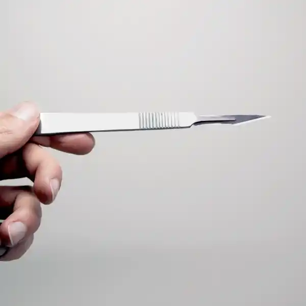 A hand holds a surgical scalpel against a light background, ready to start tissue culture using the Plant Cell Tissue Culture Starter Kit.