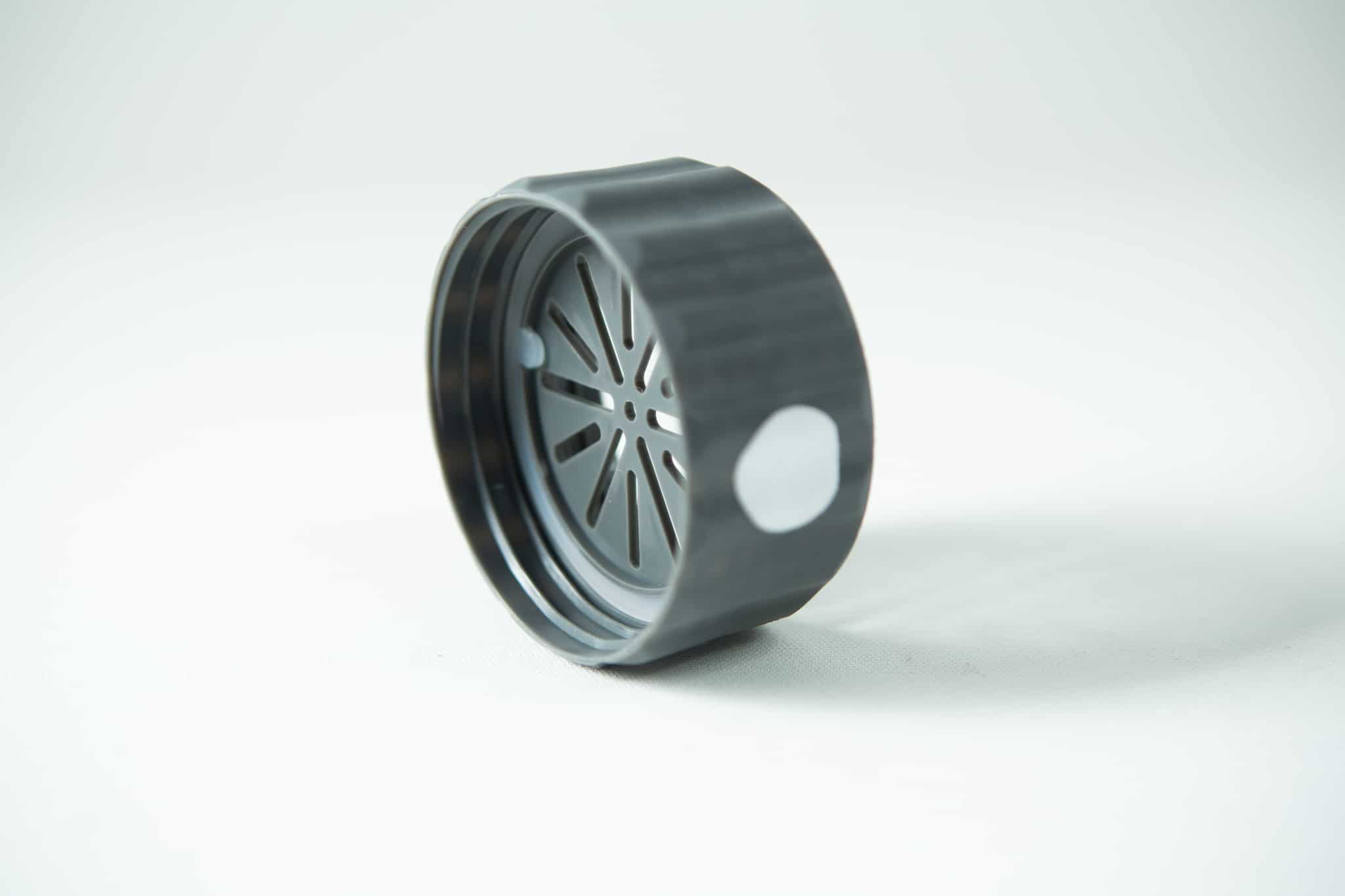 A black plastic circular lid with a slotted inner pattern, from the Plant Cell Biocoupler™ Glass Set (16oz, 12oz, 8oz), is shown on a white surface.