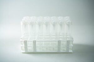 The Plant Cell Vented Plant TC Test Tubes with rack 12pc features a white plastic rack holding multiple clear test tubes with lids, displayed against a plain background.