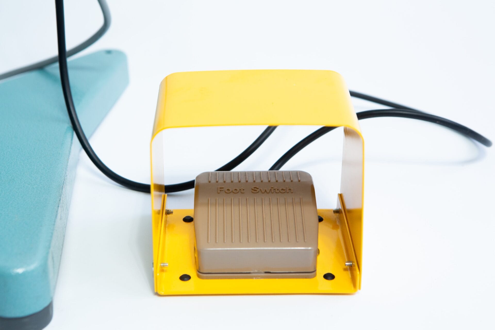 The Vertical Foot Heat Sealer VHVD 450mm Double 10mm by Venus features a yellow-covered foot switch with cable, positioned on a white surface beside green equipment.