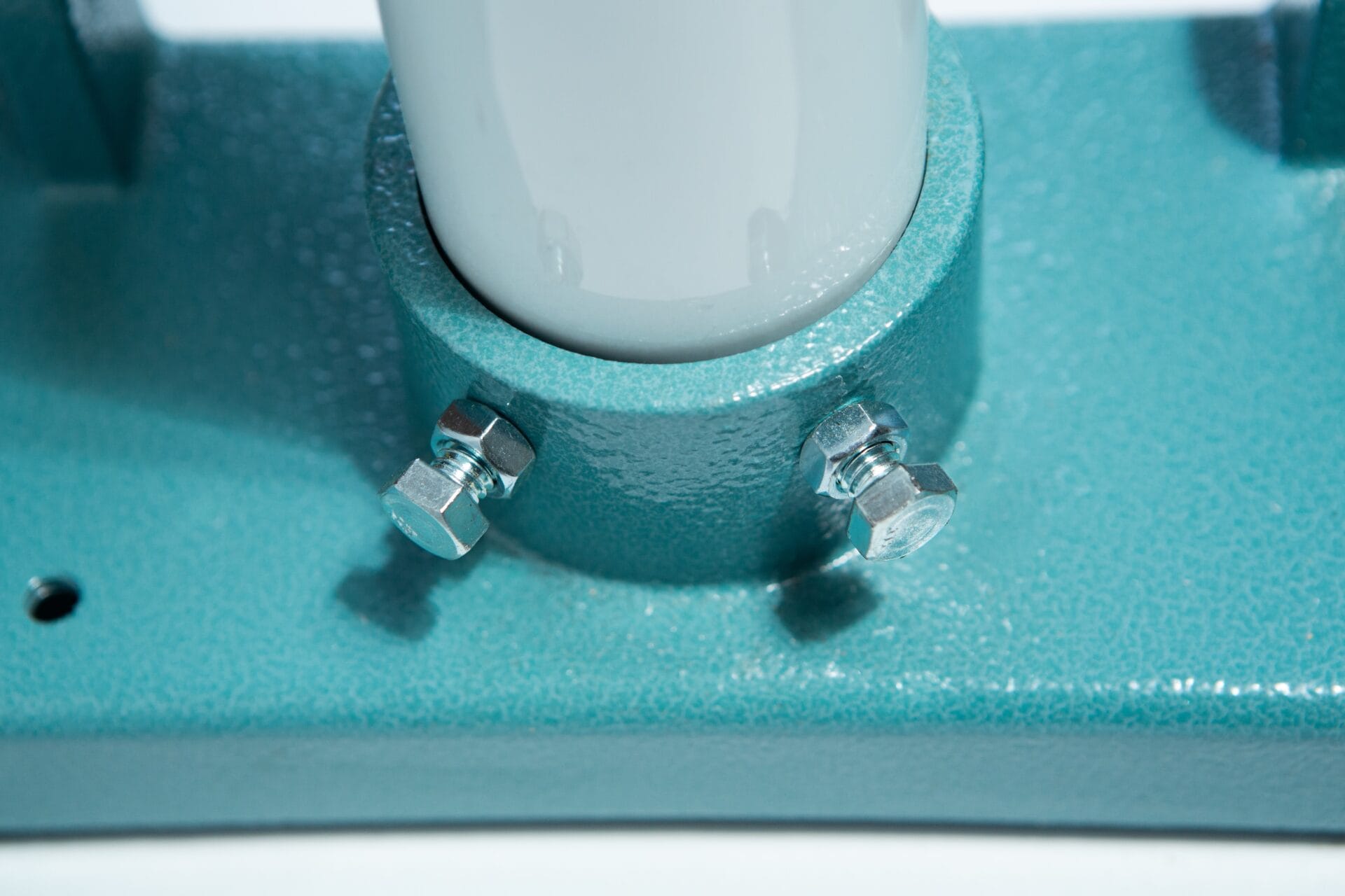 Close-up of two bolts securing the Vertical Foot Heat Sealer VHVD 450mm Double 10mm by Venus to a white cylindrical pole in a textured teal metal base.