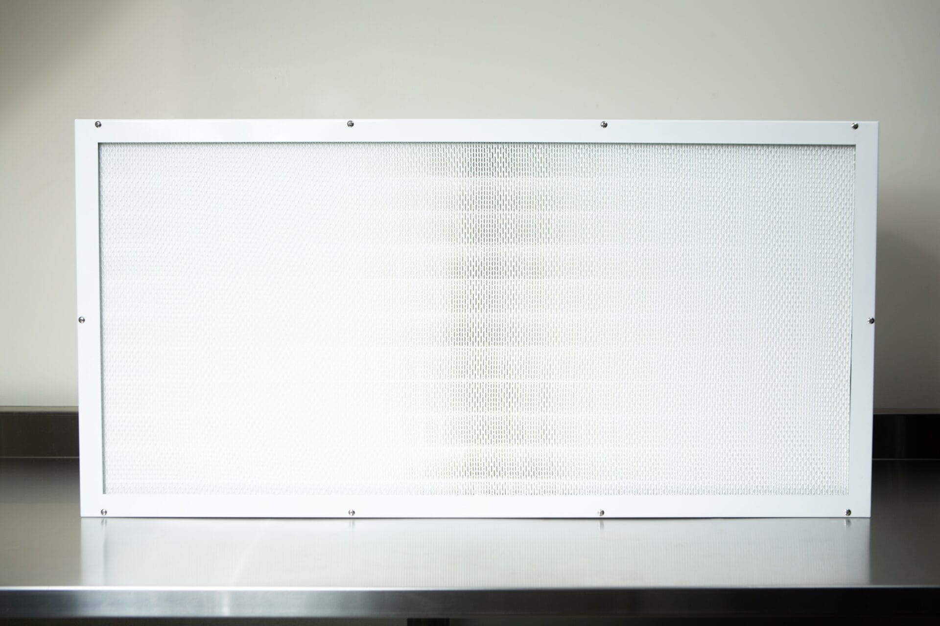 The Laminar Flow Hood H14 with pre-filter (120x60x35cm) features a rectangular white-framed air filter, shown on a metallic surface against a light background.