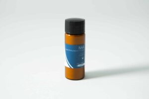Small brown plastic bottle with black cap and blue label reading "Plant Cell Naphthaleneacetic (NAA) Powder" on a white surface.
