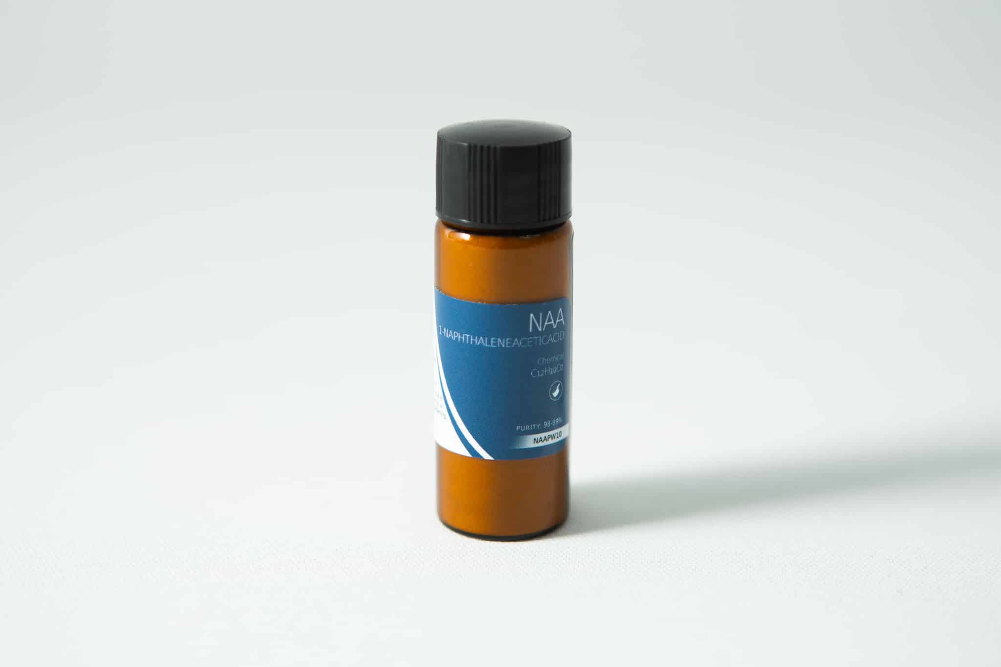 Small brown plastic bottle with black cap and blue label reading "Plant Cell Naphthaleneacetic (NAA) Powder" on a white surface.