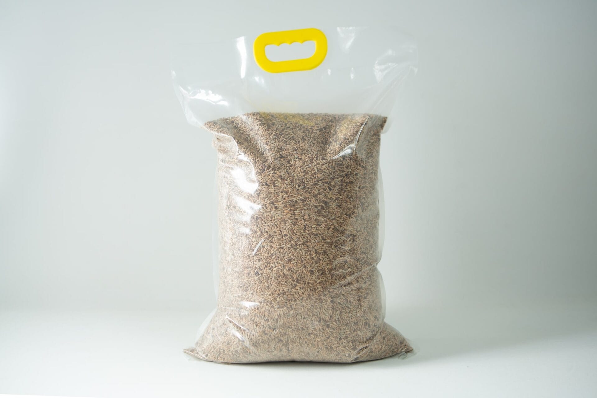 A sealed plastic bag of Certified Organic Biodynamic Rye berry grain, filled with brown grains and featuring a yellow handle at the top.