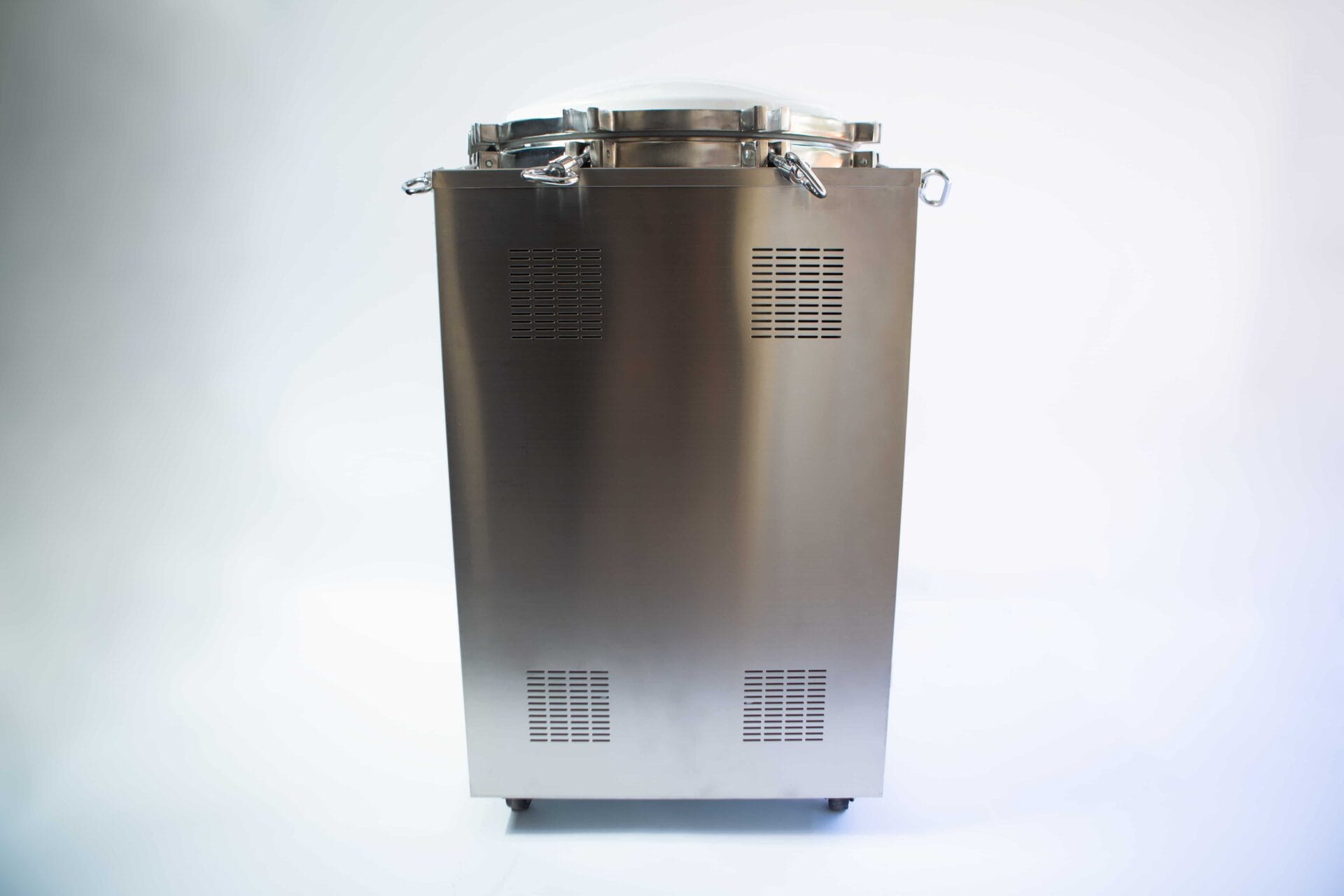 Stainless steel industrial autoclave with a closed lid and ventilation grilles, standing on a white background.